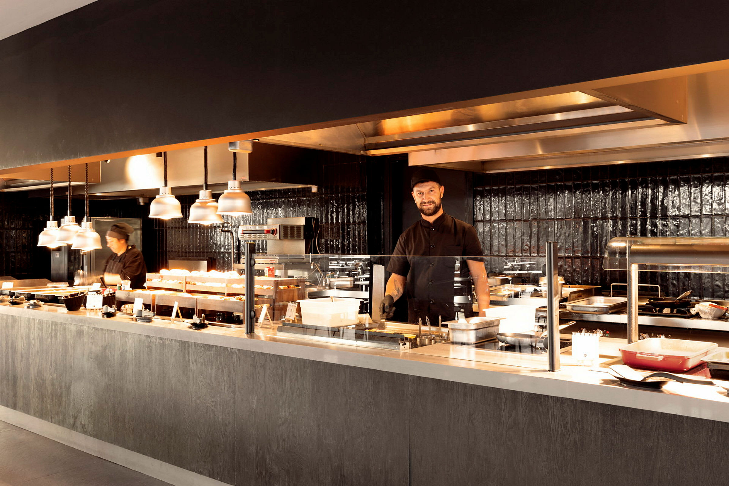 Et restaurantkjøkken med flere matstasjoner og belysning. (AI-generert tekst)