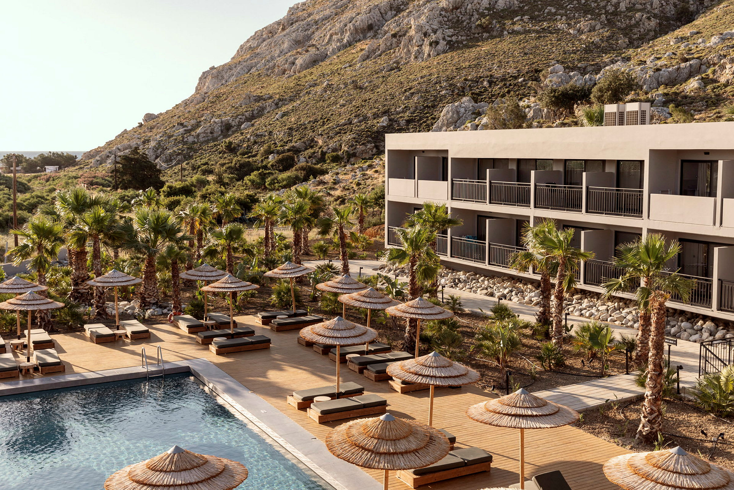 Hotellbygning med basseng og solsenger omgitt av palmer. (AI-generert tekst)