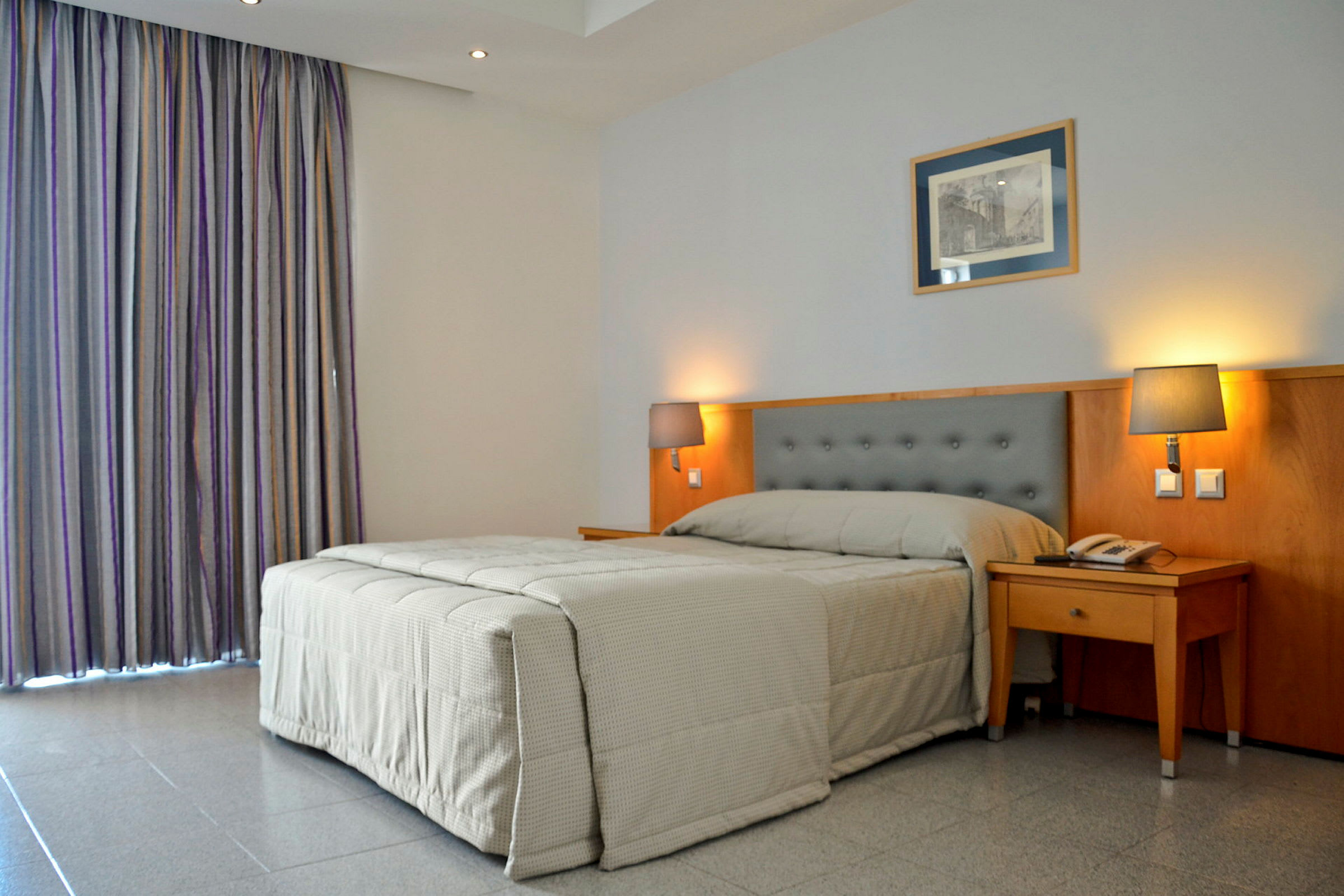 Hotellrom med en seng og to sengelamper. (AI-generert tekst)