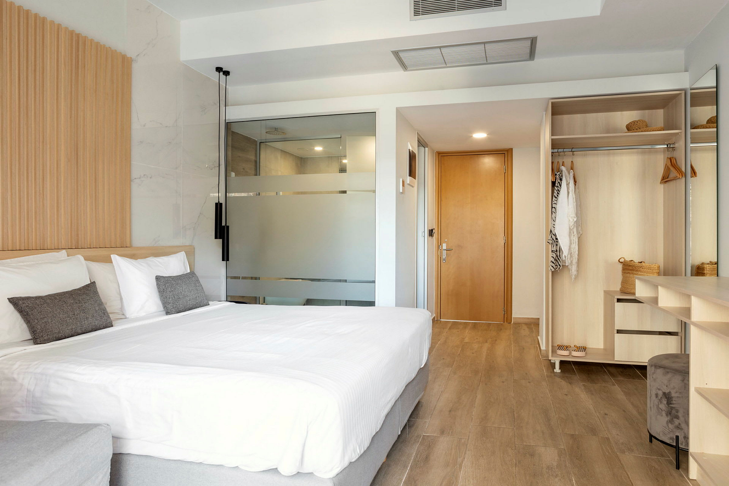 Et moderne hotellrom med stor seng, garderobe og baderomsdør. (AI-generert tekst)