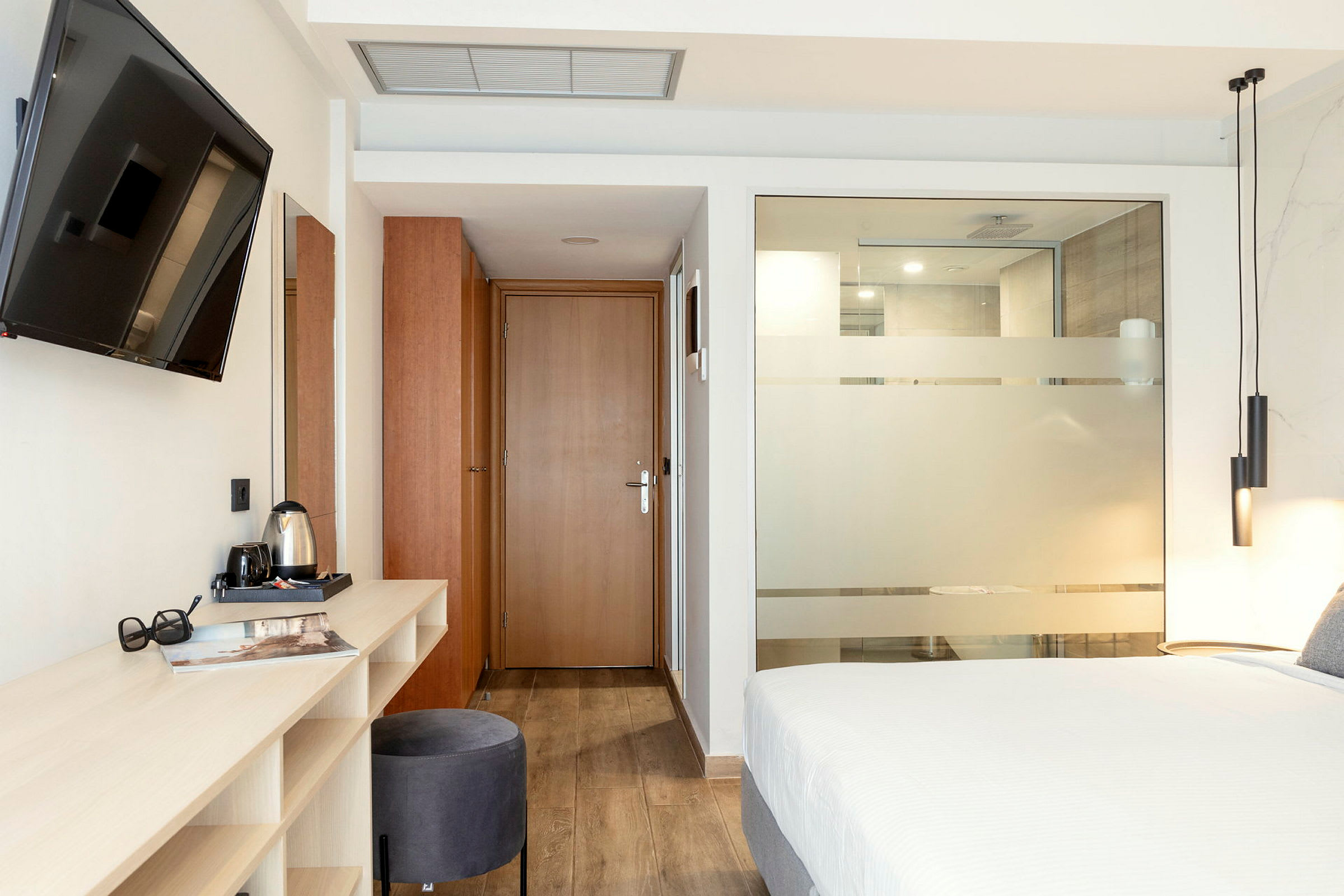 Moderne hotellrom med seng, skrivebord og TV. (AI-generert tekst)