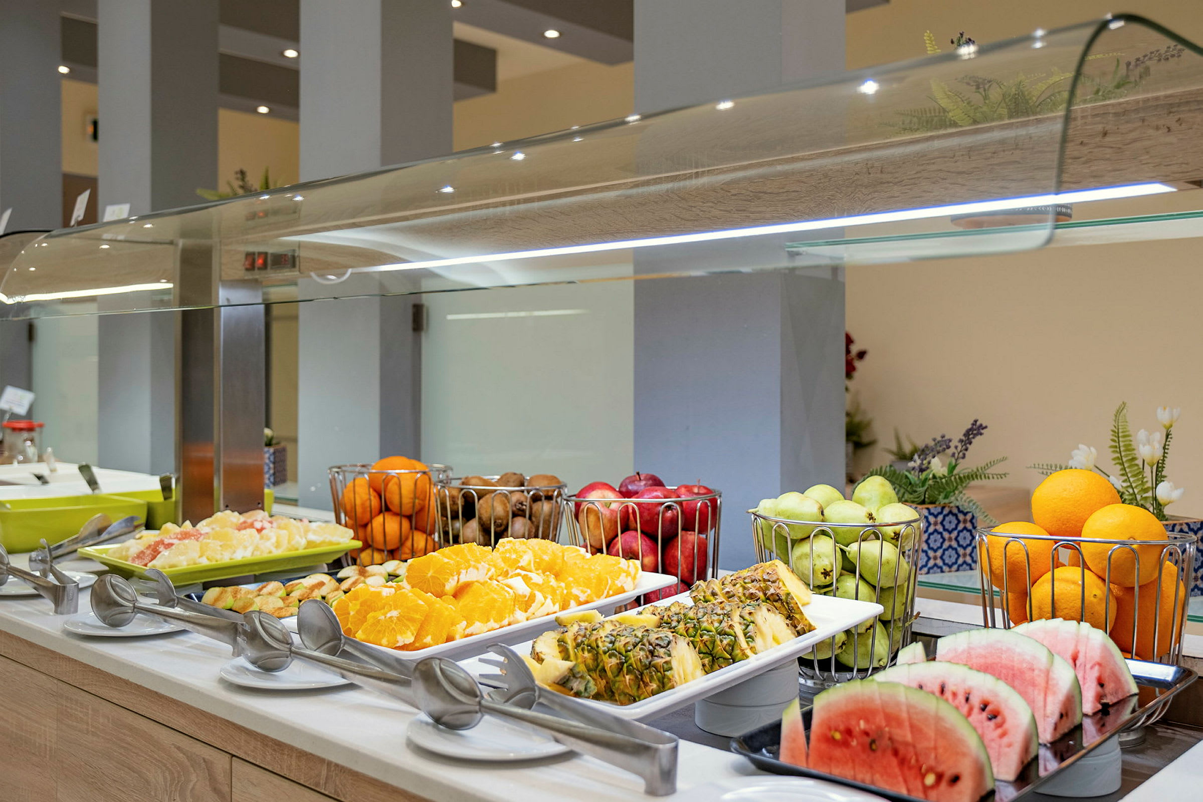 En buffet med ulike frukter, inkludert skivet vannmelon og ananas, appelsiner og druer. (AI-generert tekst)