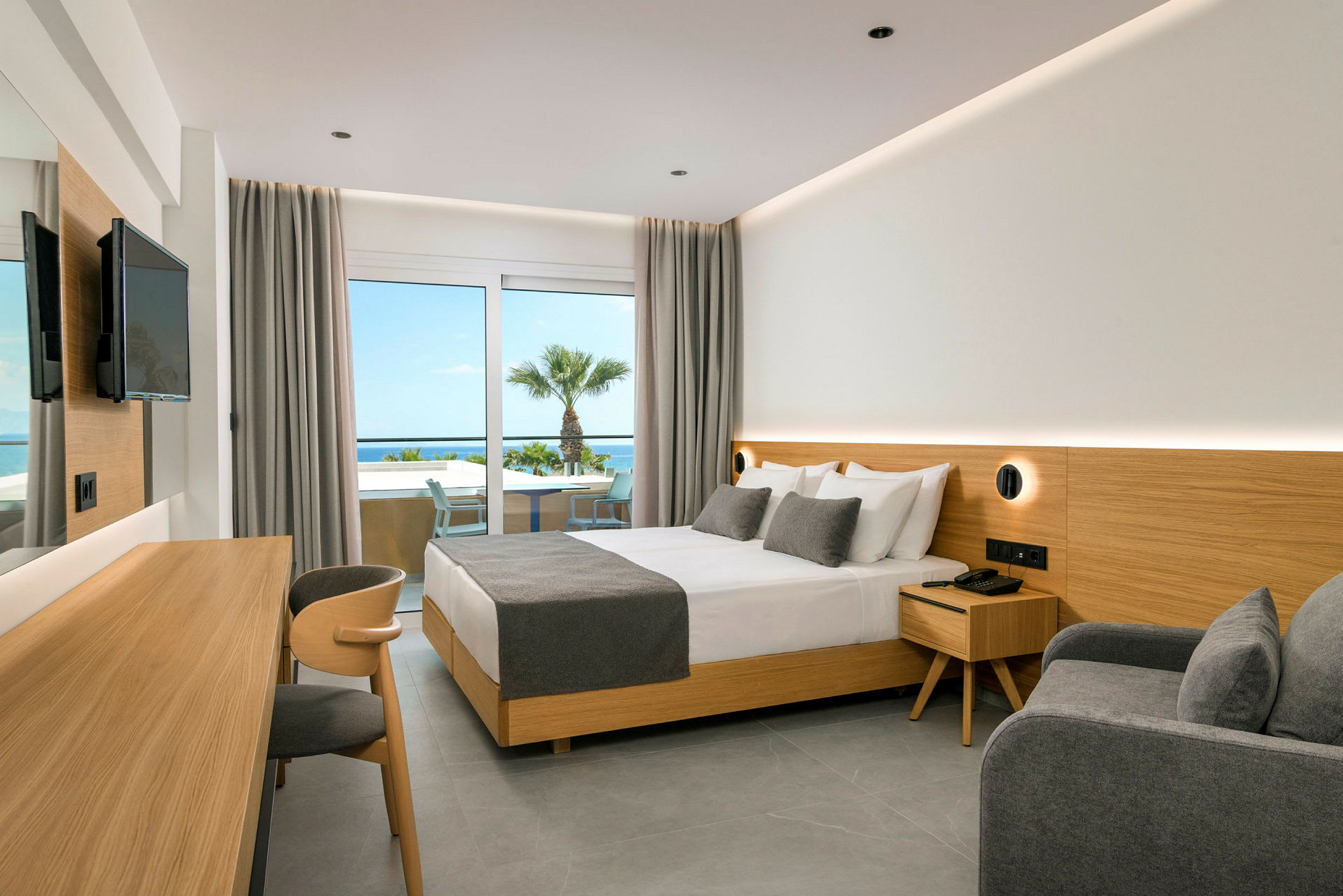 Hotellrom med dobbeltseng, grå innredning og utsikt mot havet. (AI-generert tekst)