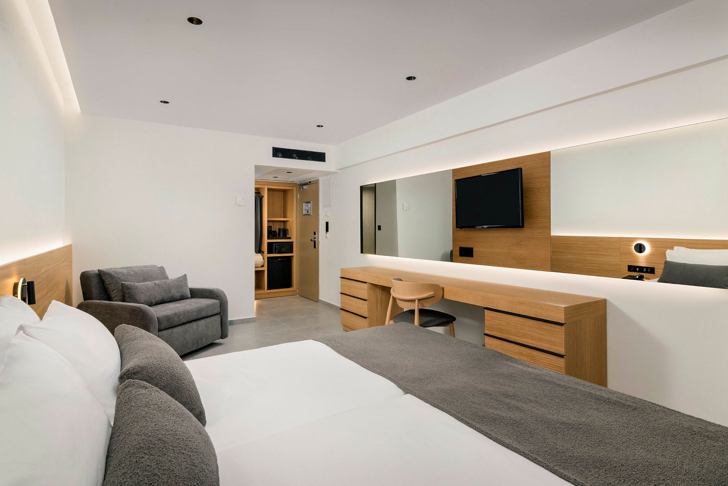 Et moderne hotellrom med dobbeltseng, skrivebord, sitteområde og TV. (AI-generert tekst)