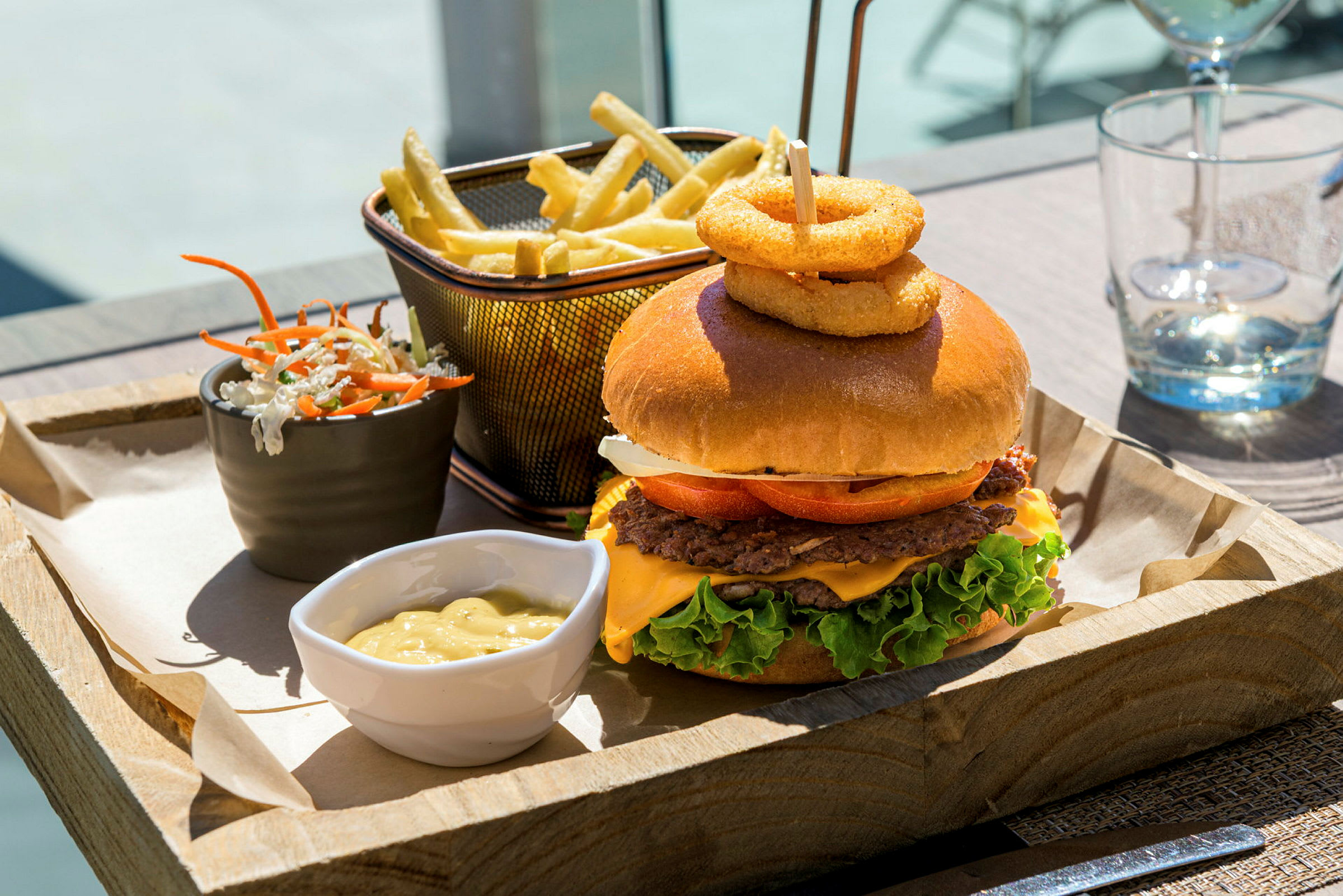 Et måltid med hamburger, pommes frites, salatblanding og saus servert på en trebrett. (AI-generert tekst)