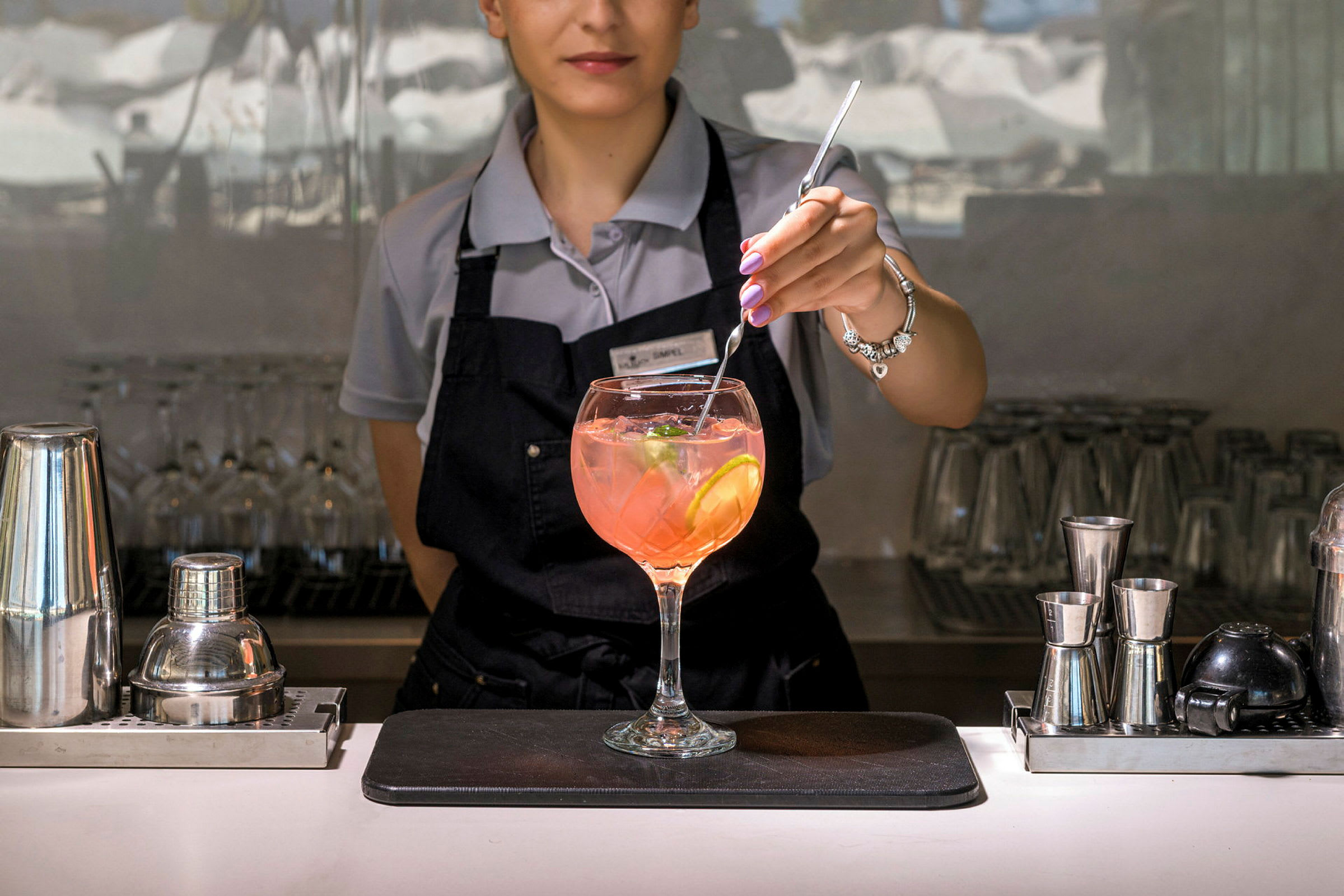 En bartender rører i en drink med sitronskiver og isbiter. (AI-generert tekst)