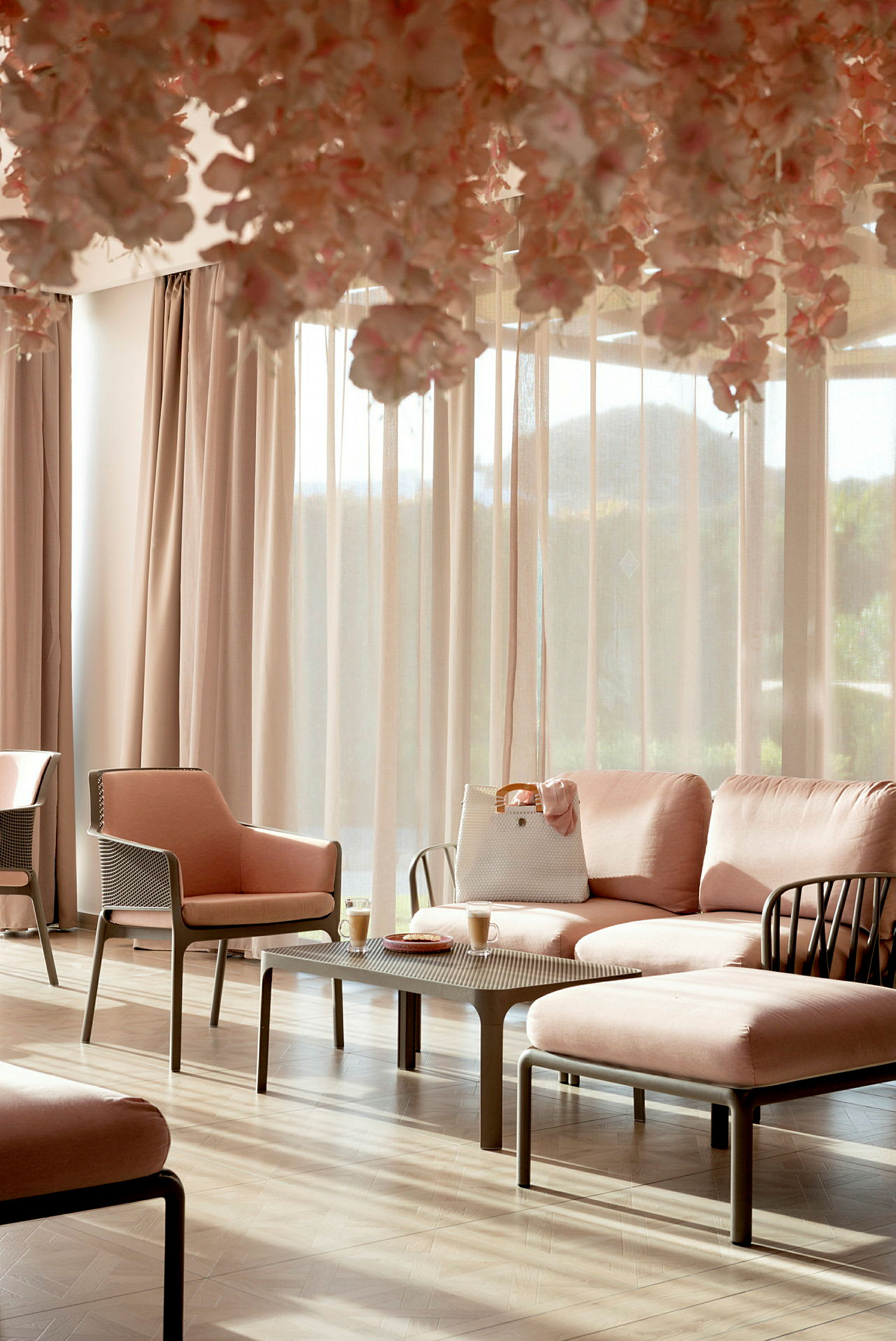 Et lyst rom med rosa stoler og sofaer, samt et bord med to kaffekopper. (AI-generert tekst)