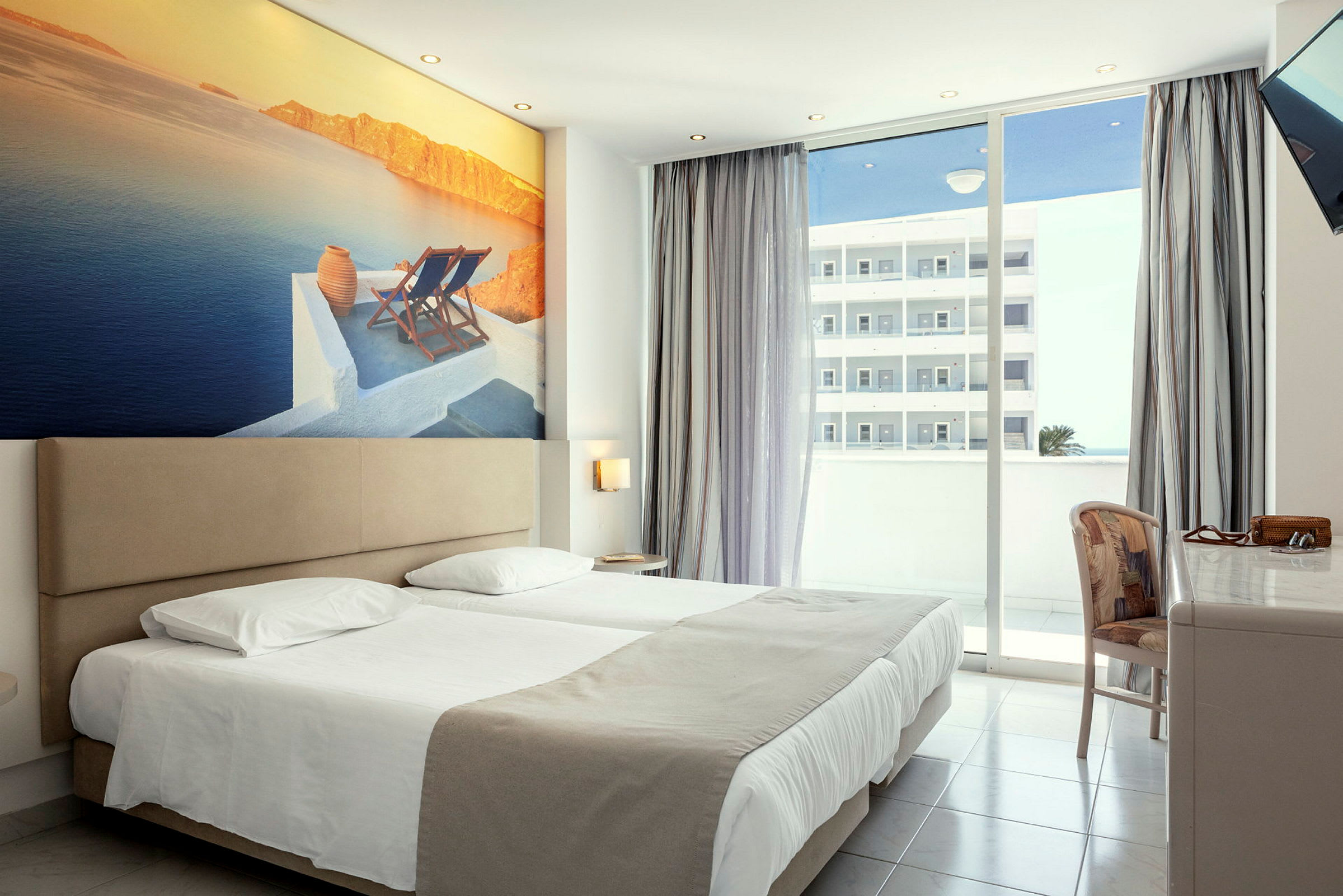Hotellrom med dobbeltseng, stort veggbilde av kystlandskap og balkong med utsikt. (AI-generert tekst)