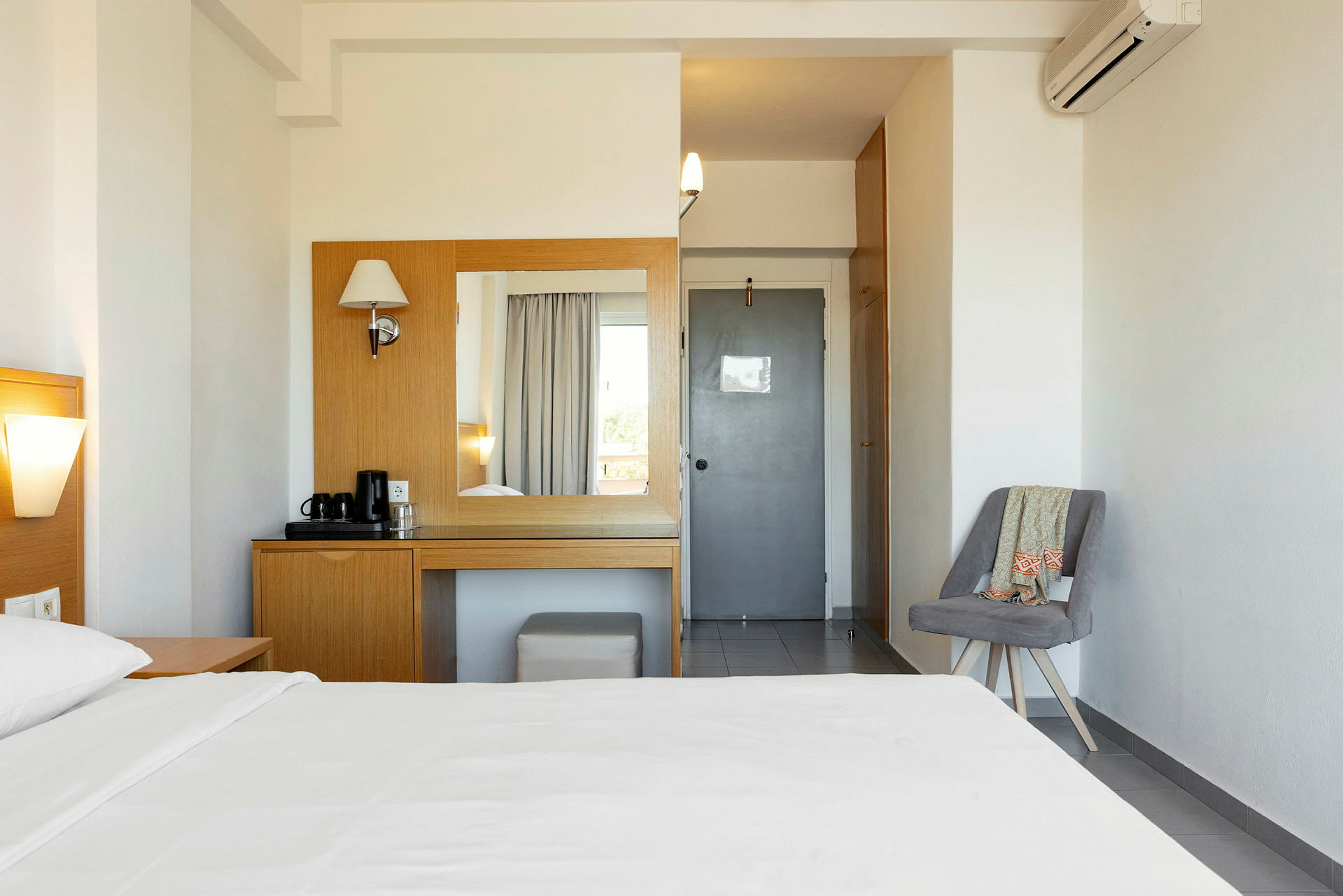Et hotellrom med en seng, et bord og speil for toalettartikler, samt en stol på siden. (AI-generert tekst)