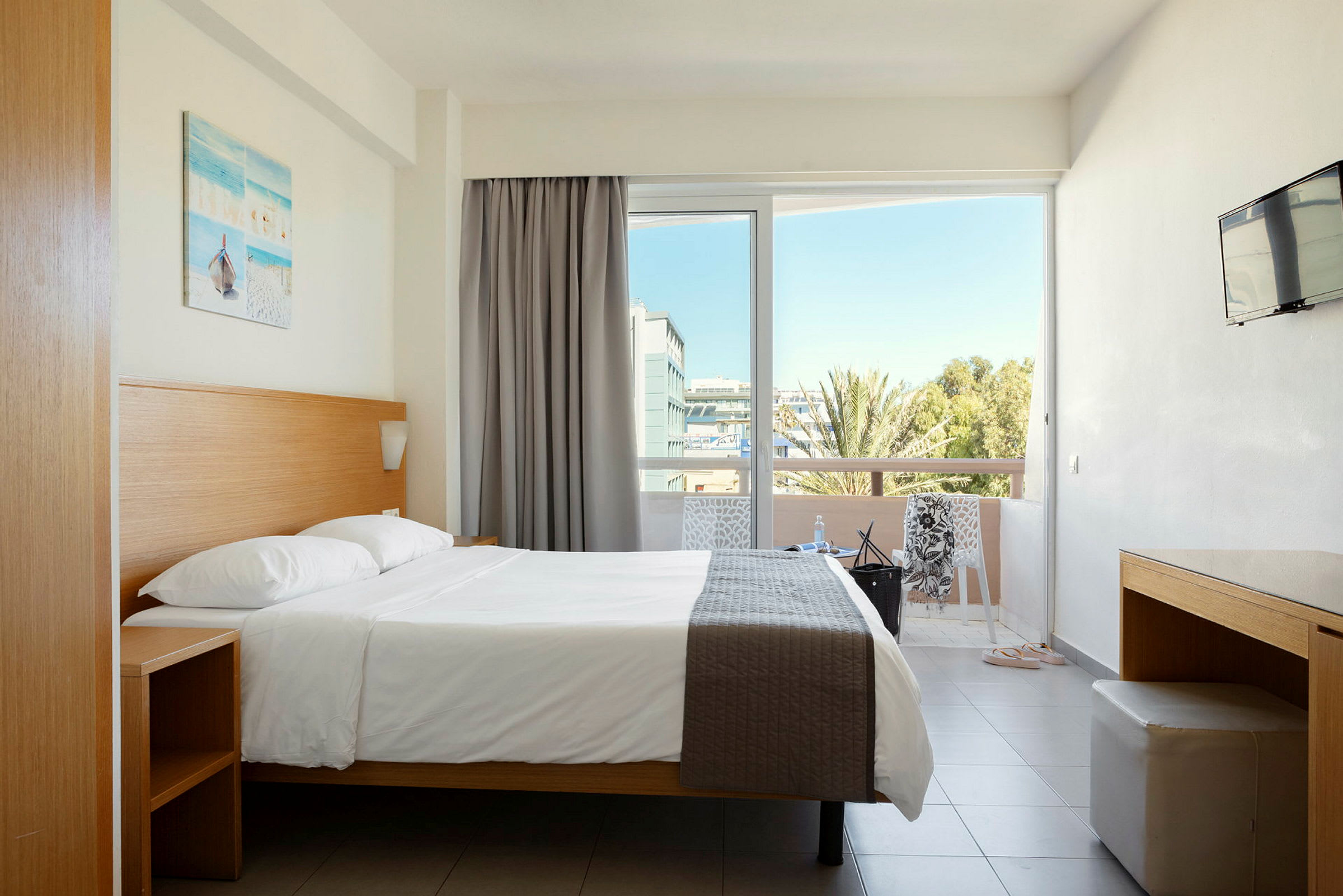 Hotellrom med dobbeltseng, balkong og utsikt. (AI-generert tekst)