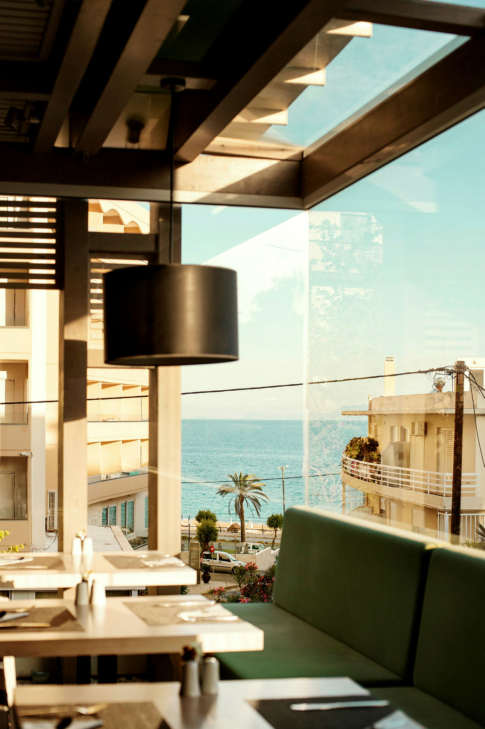 Utsikt fra restaurant med sitteplasser innendørs og havet i bakgrunnen. (AI-generert tekst)