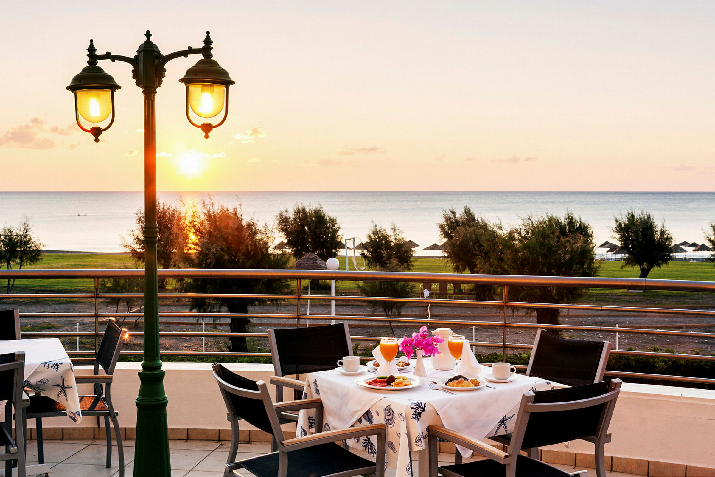 Utsikt over et bord med frokostservering på en terrasse med havet i bakgrunnen. (AI-generert tekst)