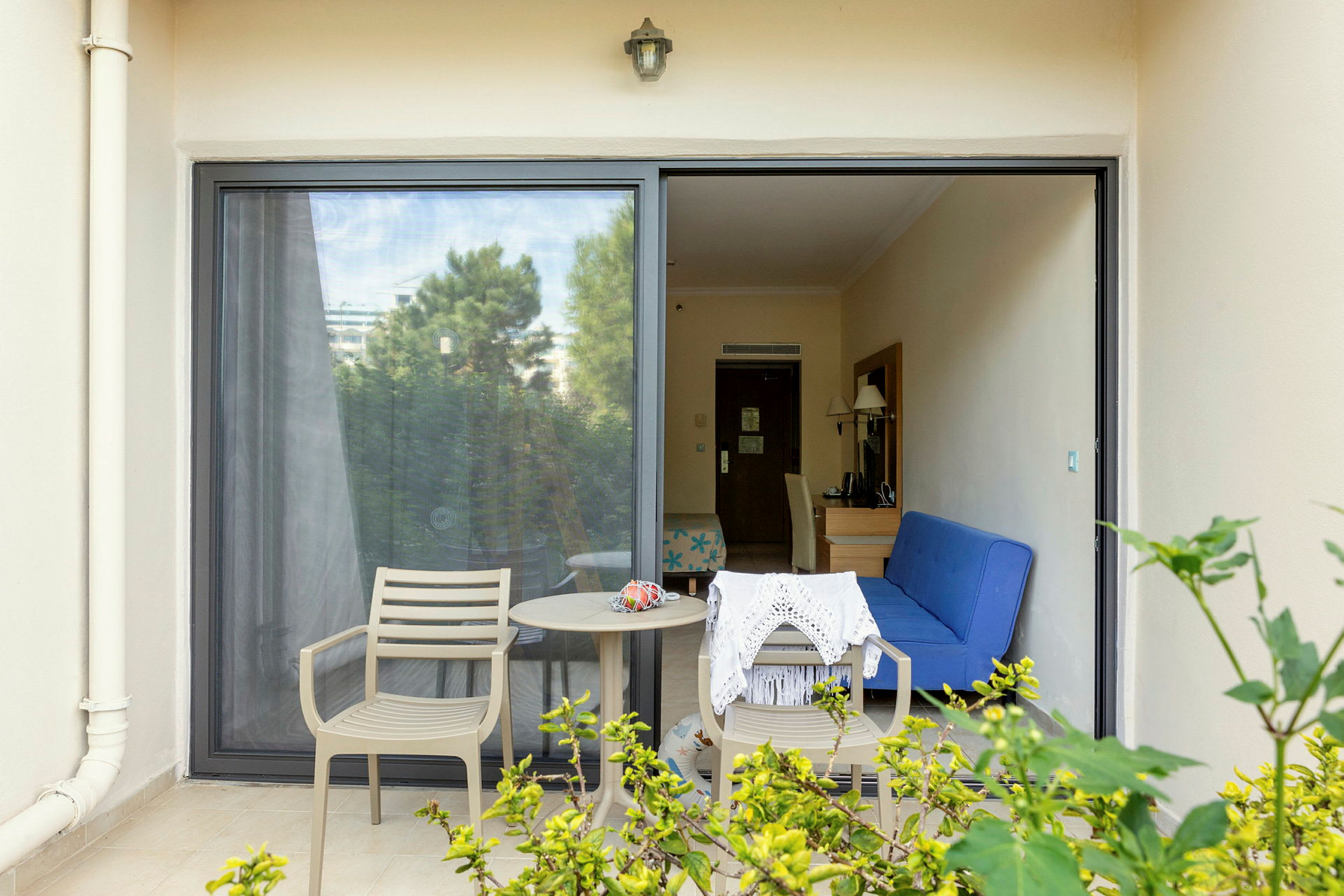 Bilde av en terrasse med to stoler, et bord og utsikt inn i et hotellrom. (AI-generert tekst)