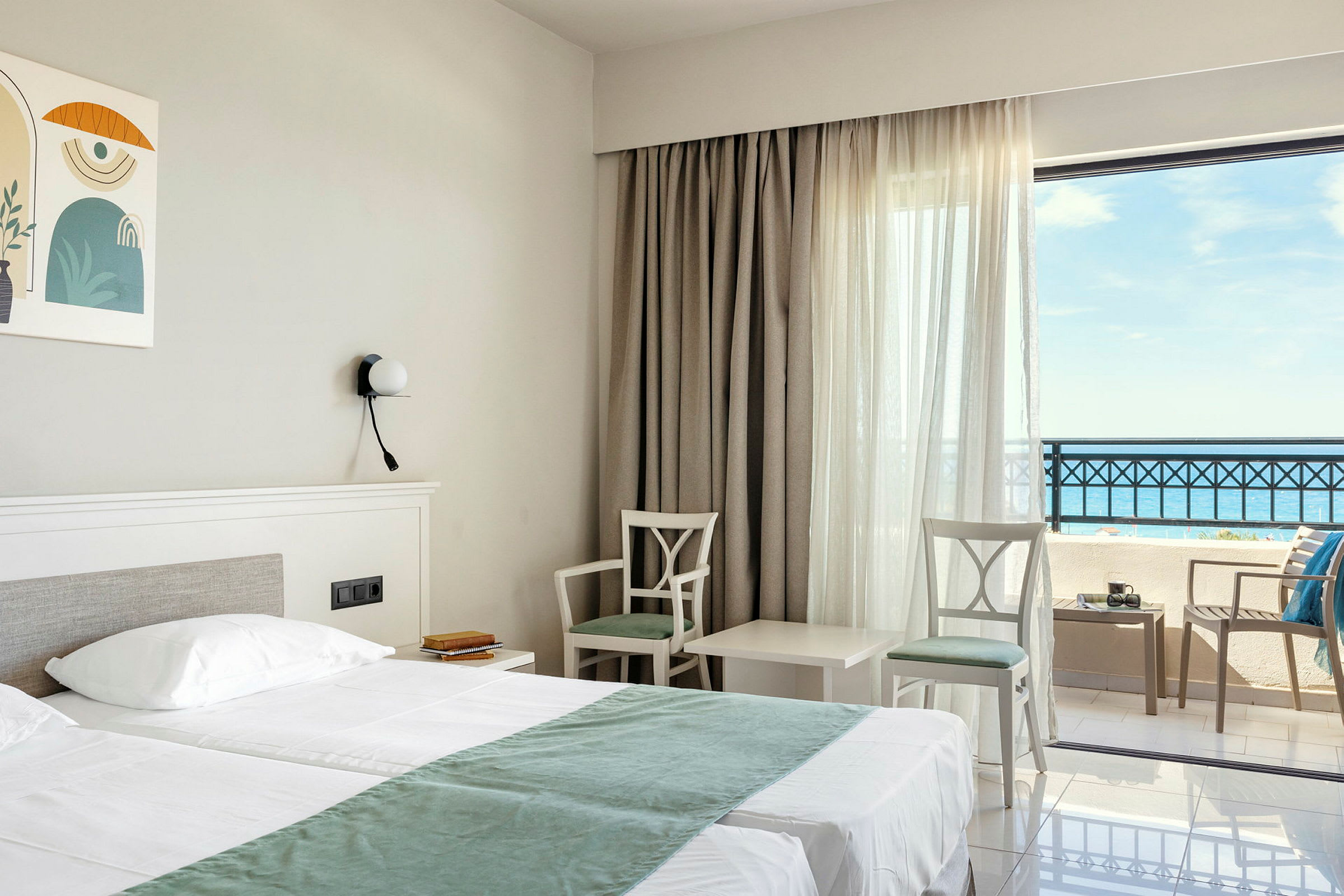 Hotellrom med dobbeltseng, to stoler og et bord ved vindu med havutsikt. (AI-generert tekst)