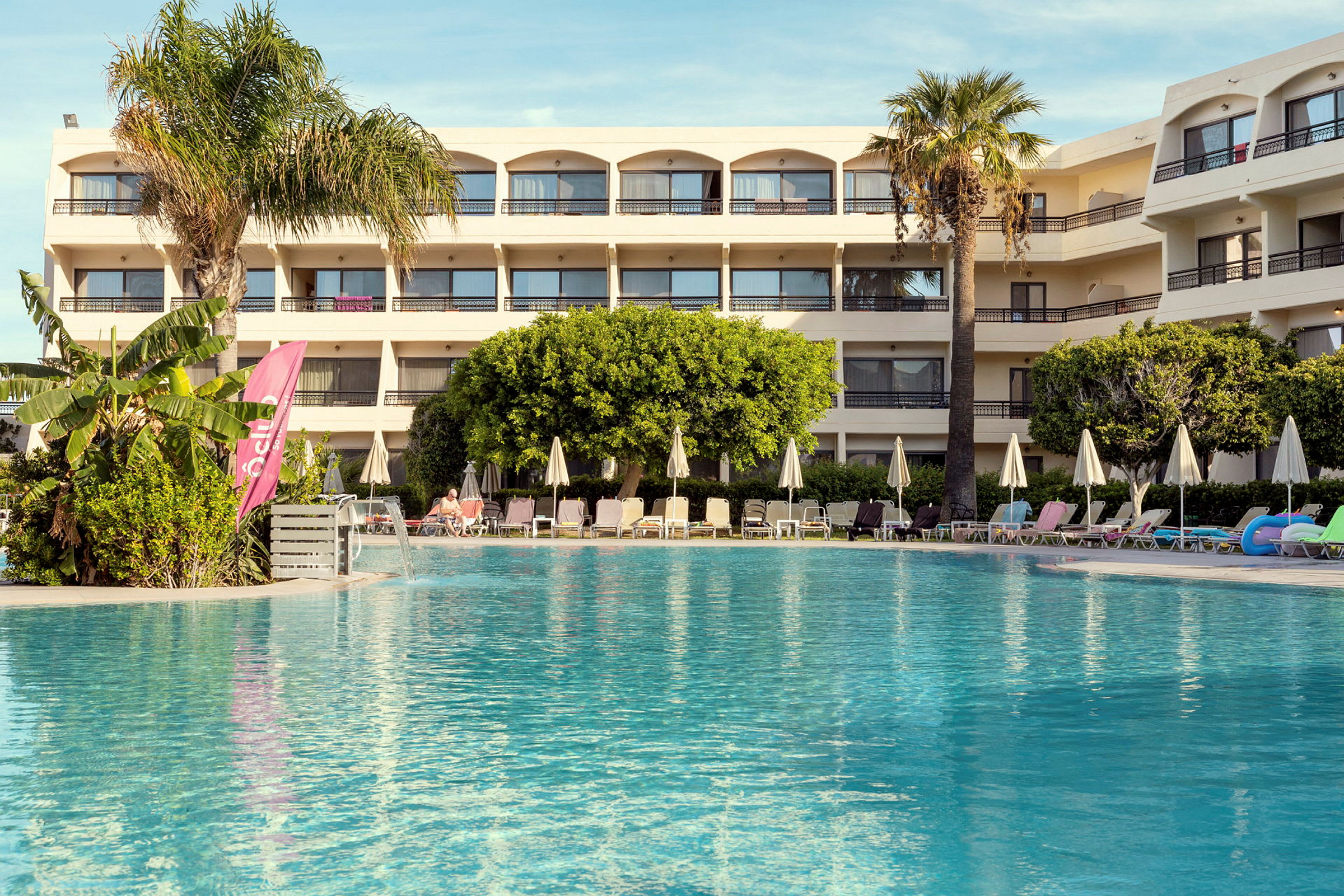 Hotell med basseng og solsenger i forgrunnen. (AI-generert tekst)