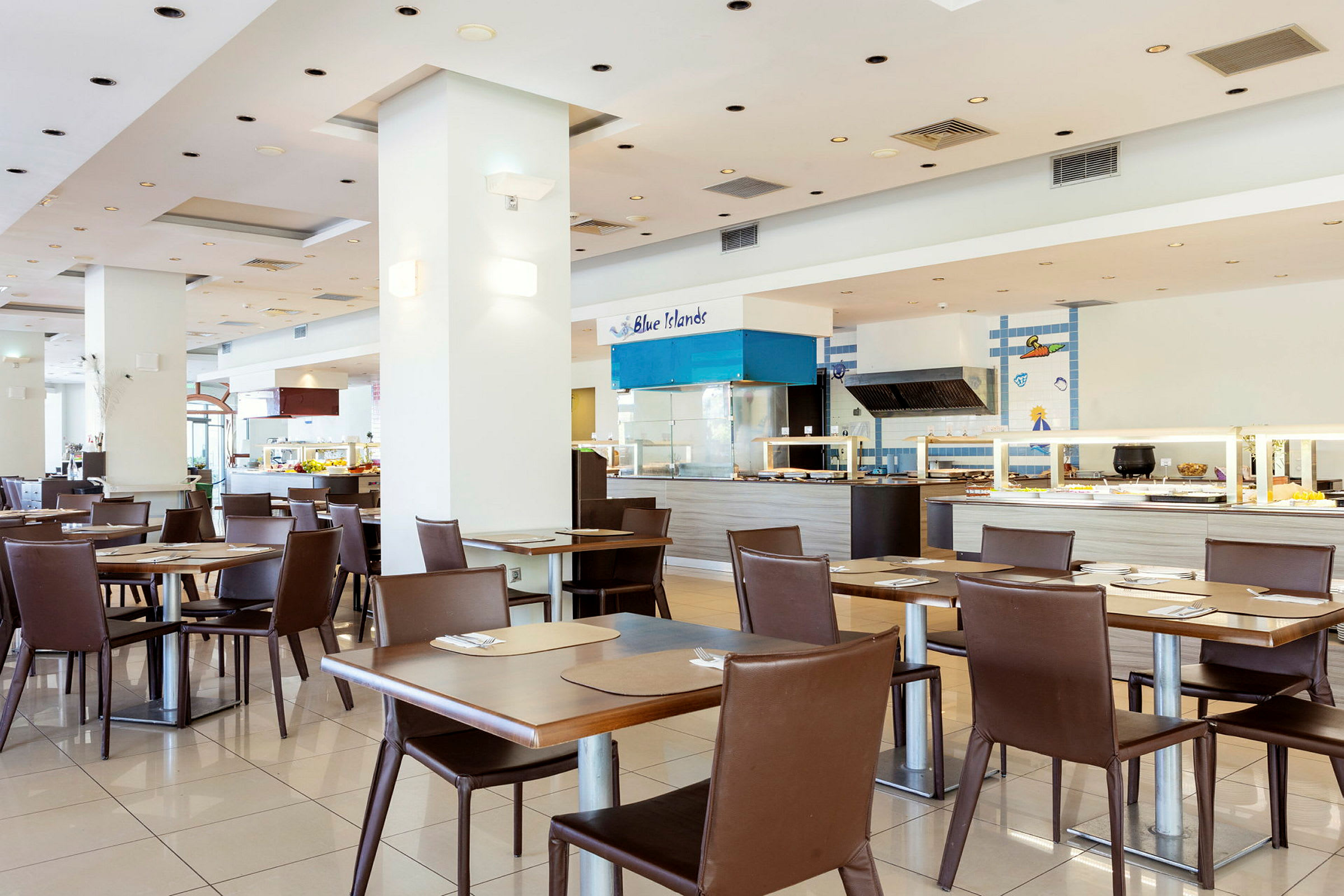 Restaurant med moderne bord og stoler samt en serveringsdisk i bakgrunnen. (AI-generert tekst)