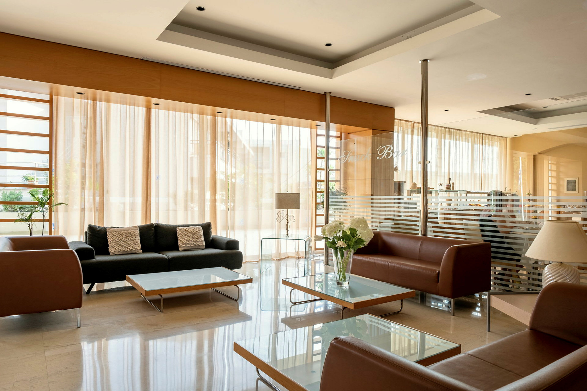 Hotellobby med sofaer og glassbord. (AI-generert tekst)
