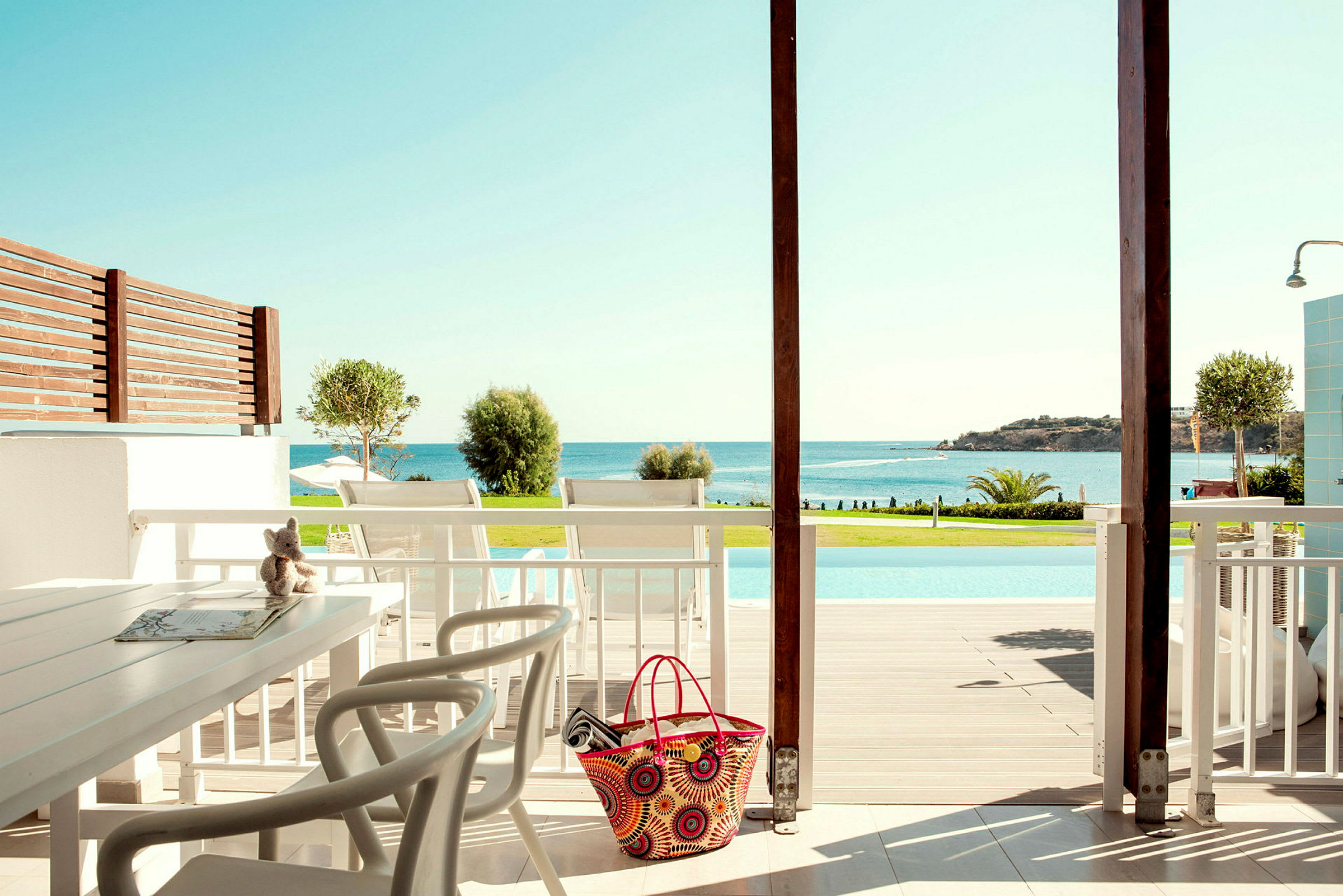 Utsikt fra en terrasse med sittegruppe mot et basseng og havet. (AI-generert tekst)