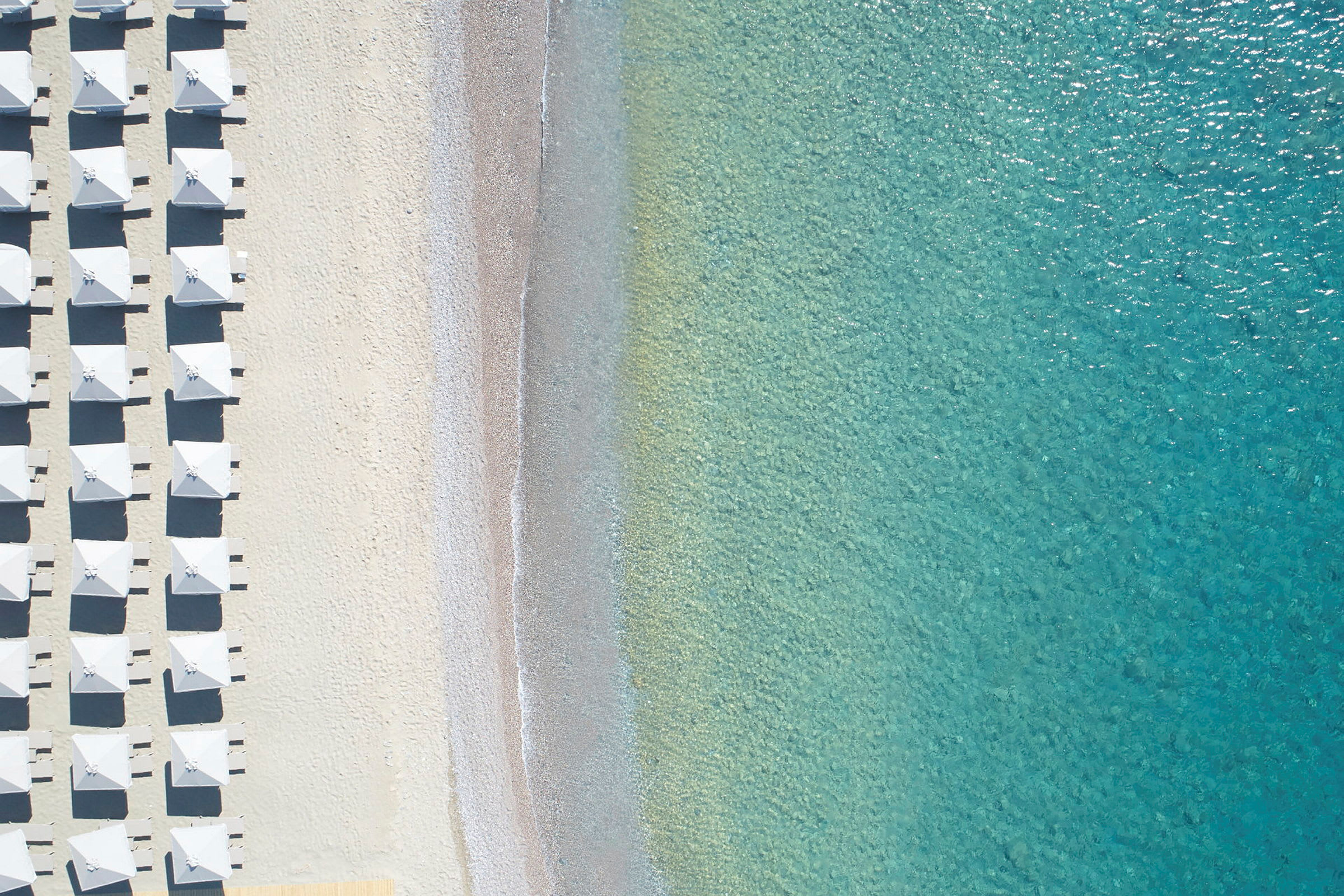 Luftfoto av strand med parasoller og klart turkis vann. (AI-generert tekst)