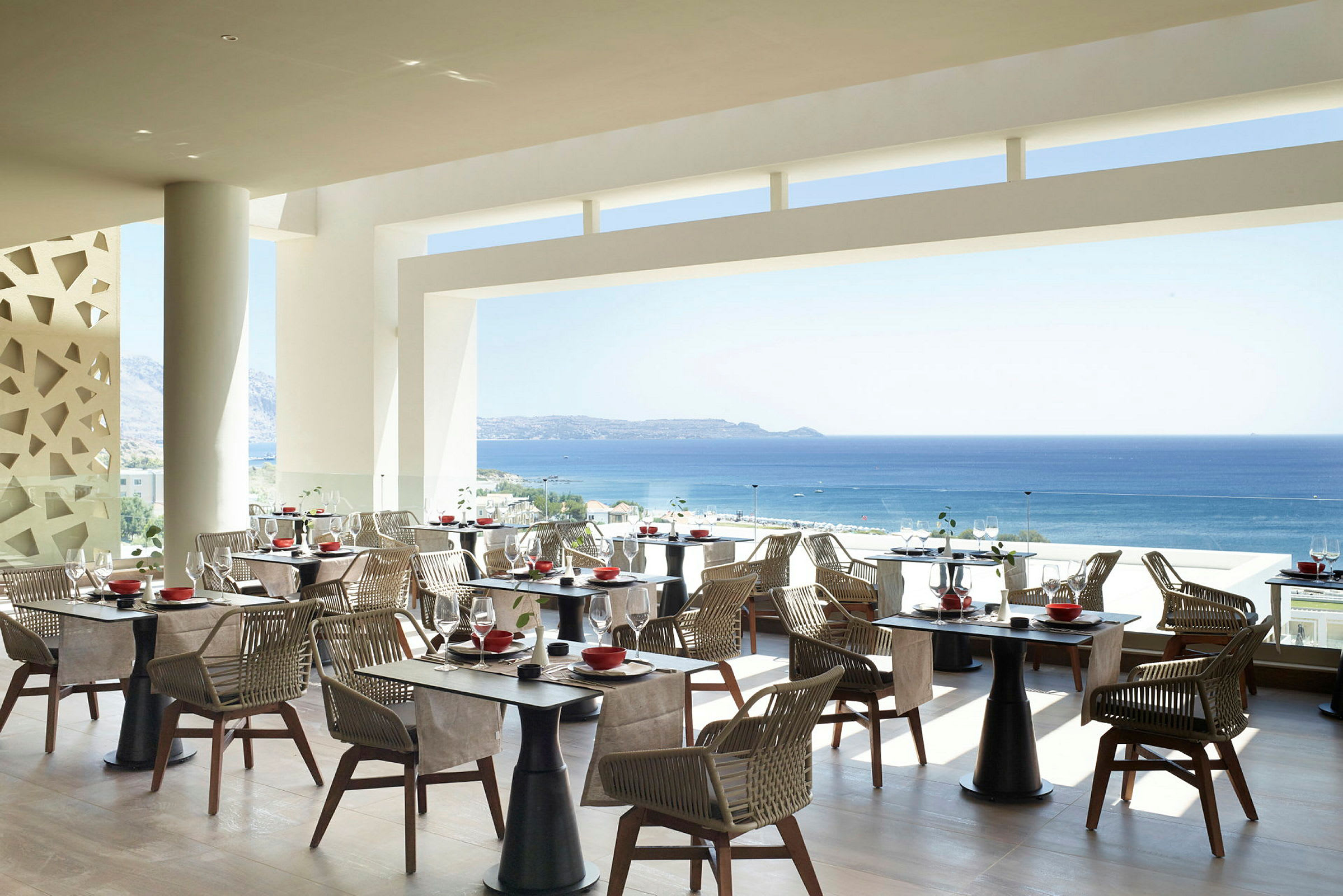 Bilde av en restaurant med utsikt over havet, med bord og stoler i en moderne innredning. (AI-generert tekst)