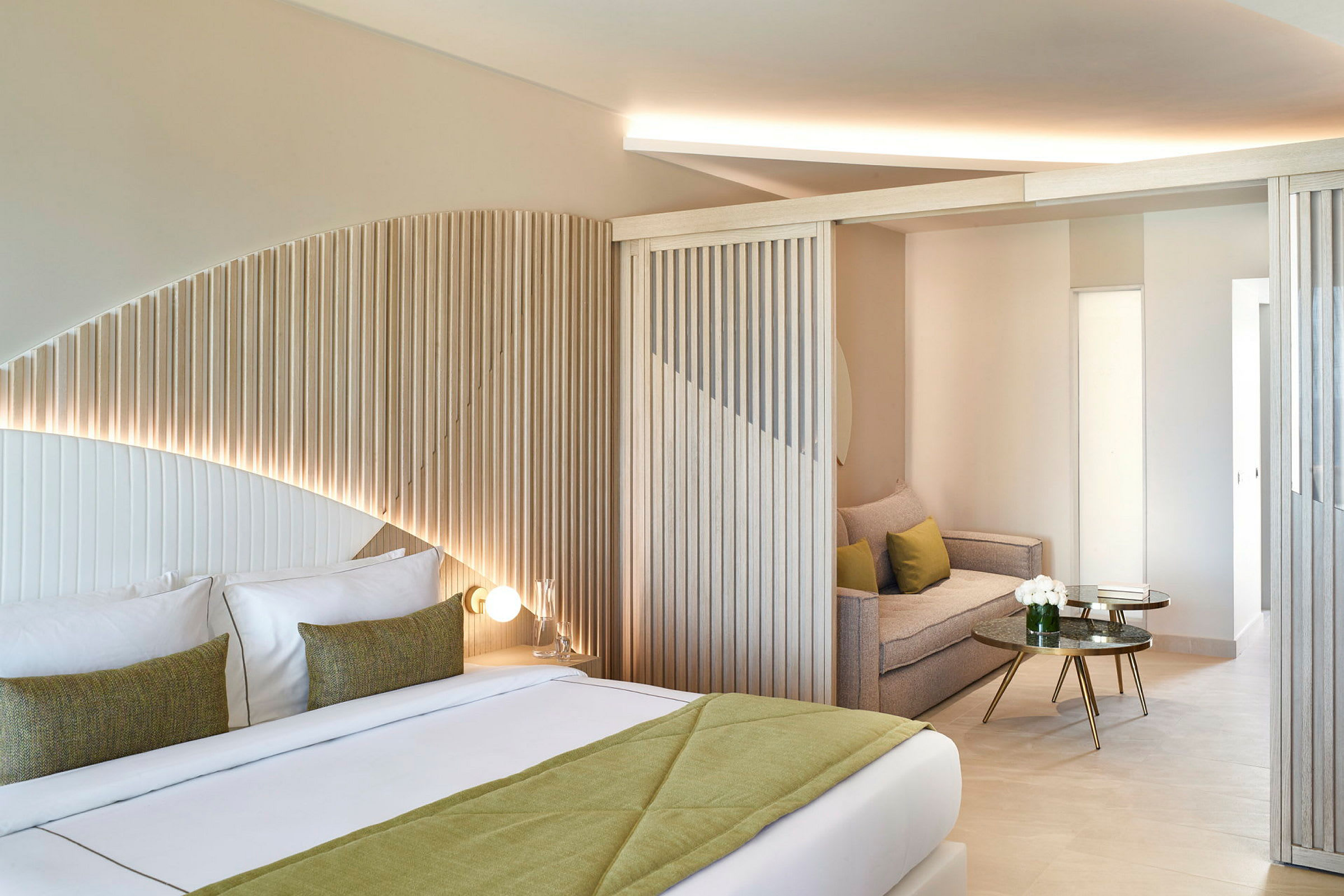 Moderne hotellrom med avrundet trepanel, dobbeltseng og sittegruppe. (AI-generert tekst)