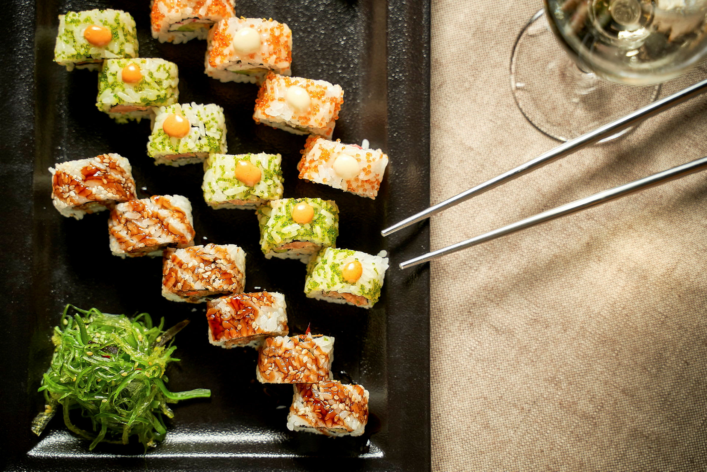 Sushi servert på en svart tallerken med sjøgressalat ved siden av. (AI-generert tekst)
