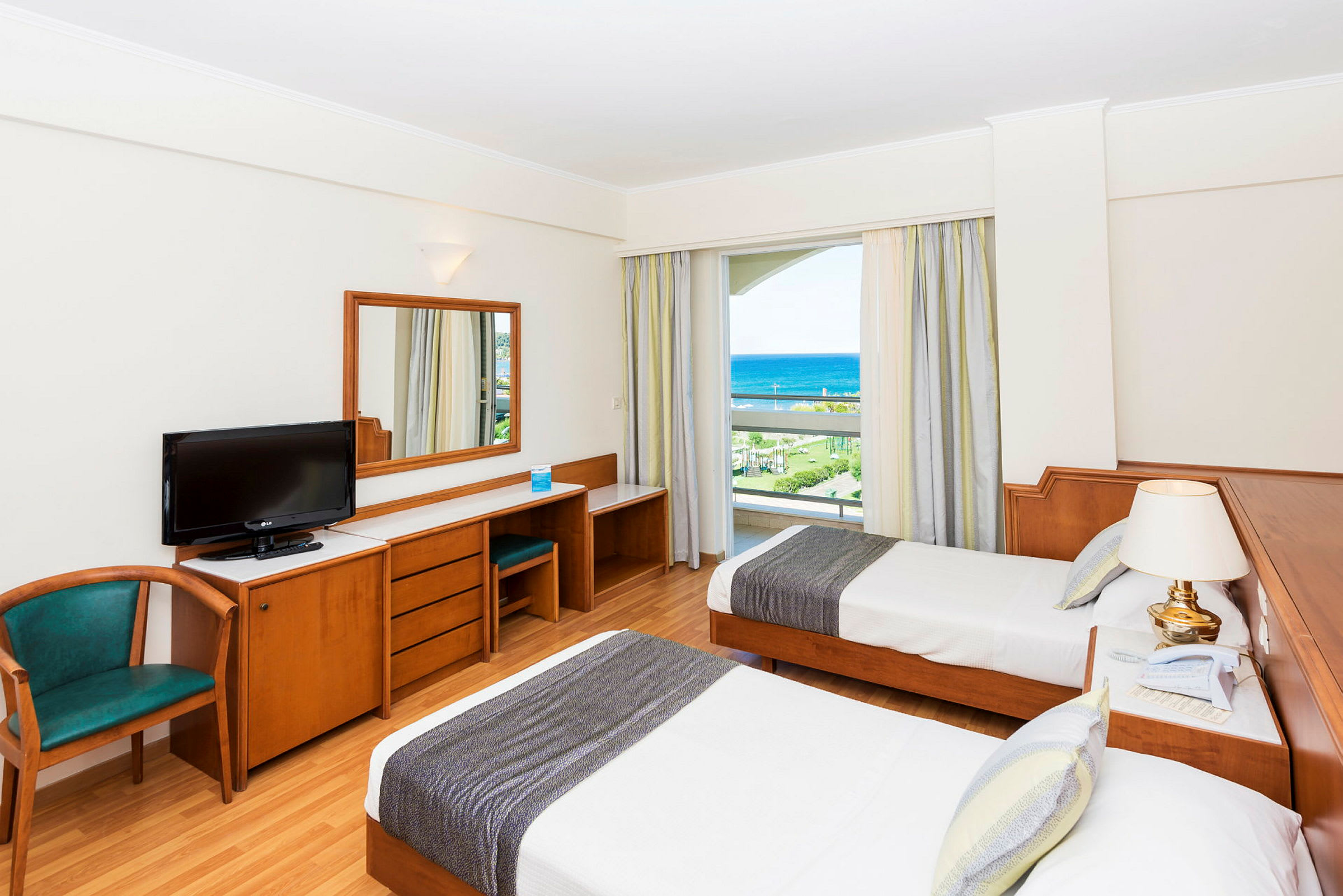 Hotellrom med to enkeltsenger, skrivebord, stol og havutsikt. (AI-generert tekst)
