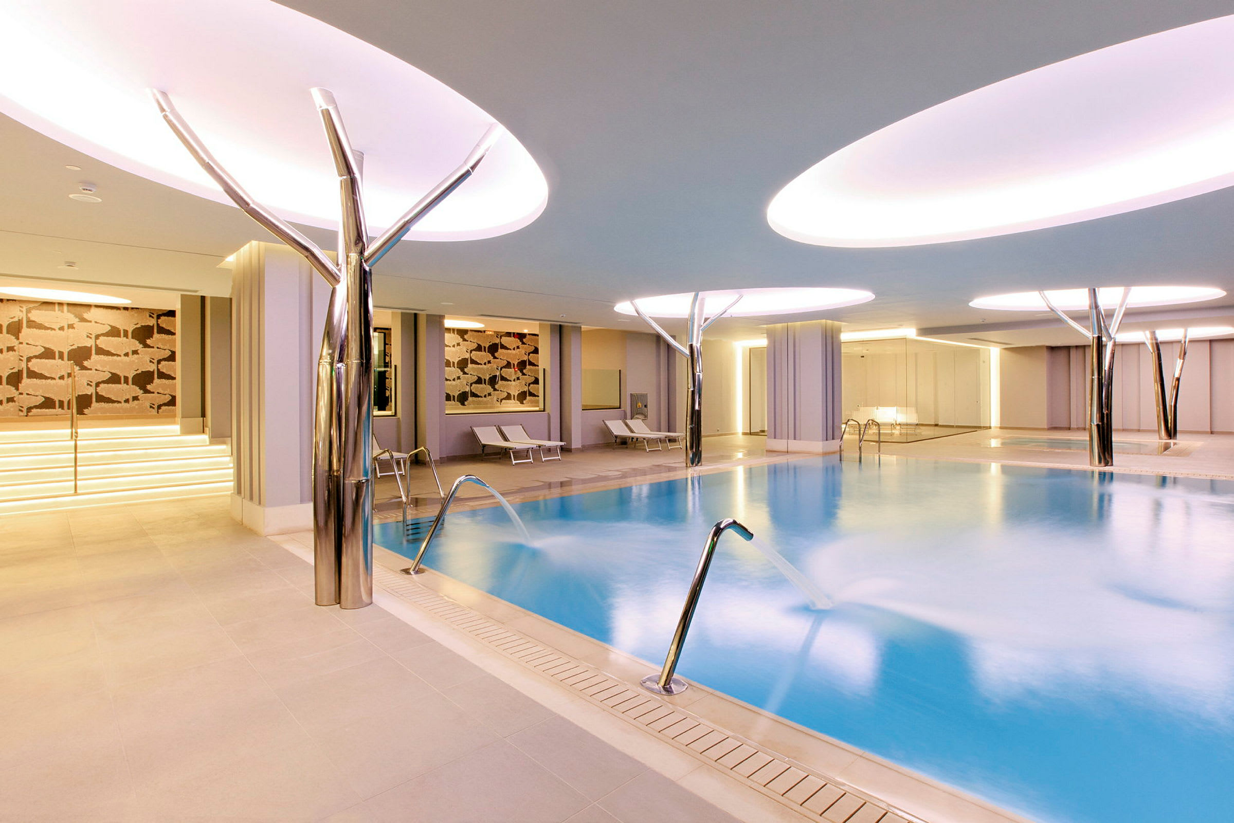 Bilde av et moderne innendørsspa med basseng og lounge-stoler. (AI-generert tekst)