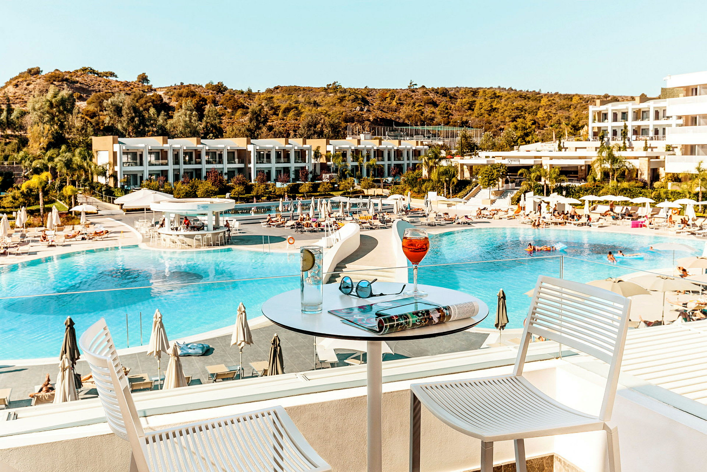 Hotellbassengområde sett fra en terrasse med drikke på et bord. (AI-generert tekst)