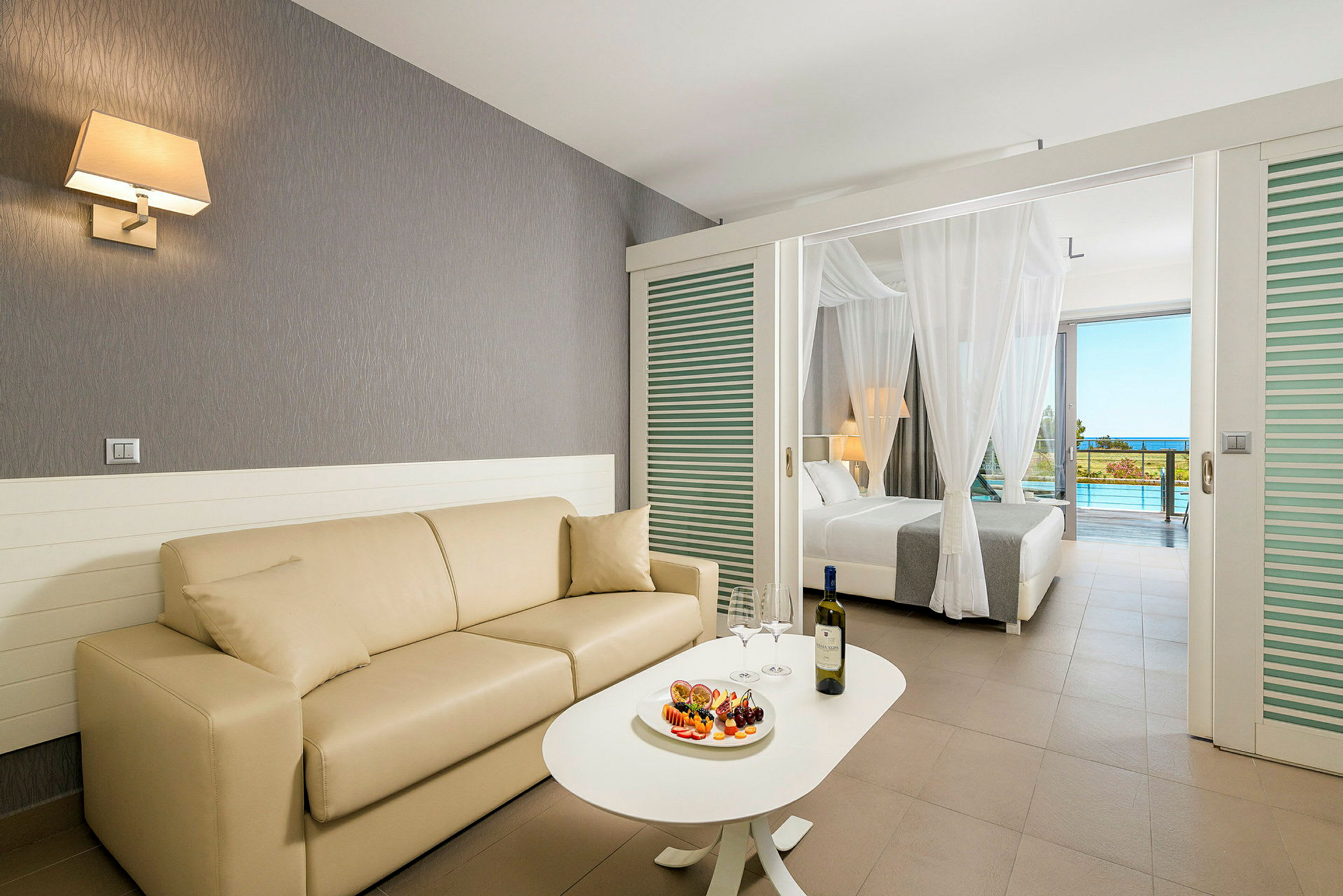Et hotellrom med sofa og seng, med et bord med frukt og vin. (AI-generert tekst)