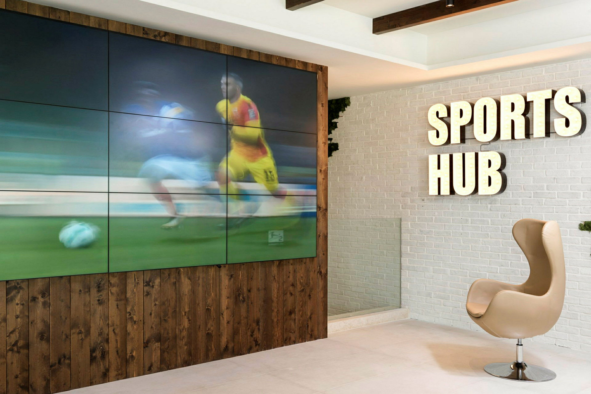 Interiør med et skilt som sier 'Sports Hub' og en skjerm som viser sport. (AI-generert tekst)