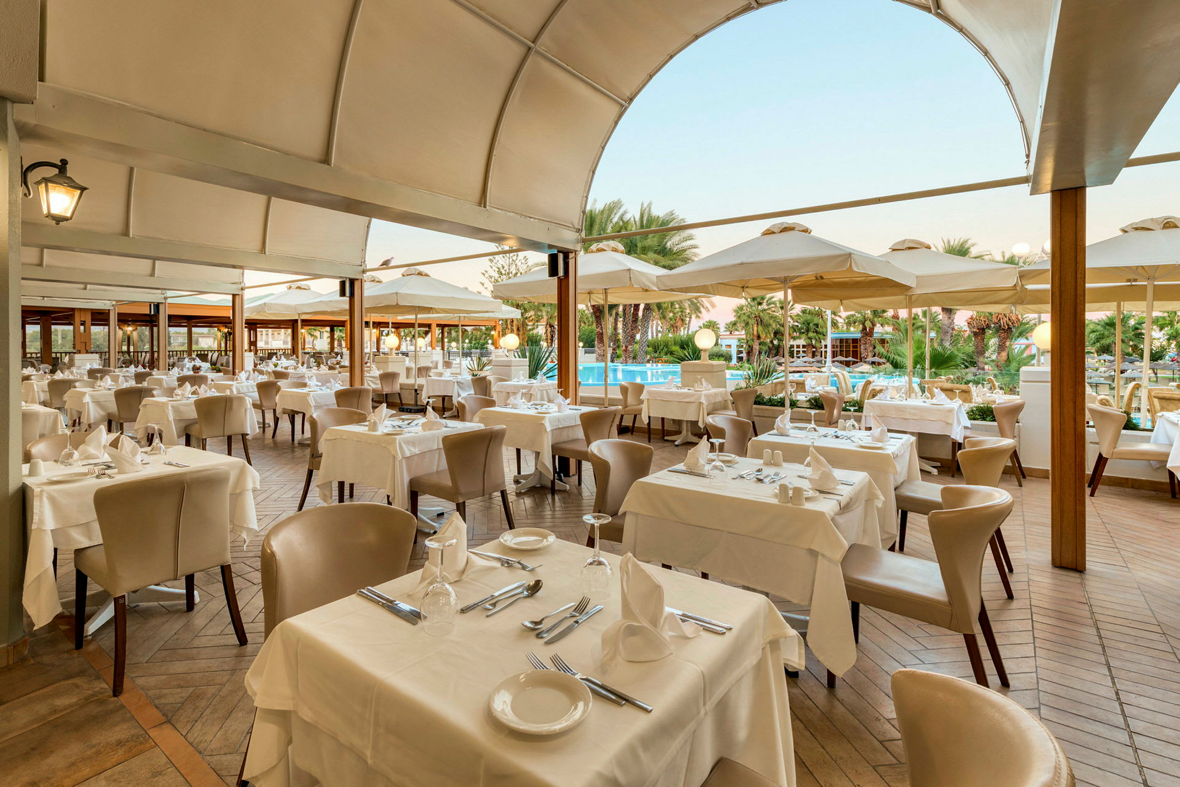 Restaurant med dekkede bord og stoler under en overbygd terrasse. (AI-generert tekst)