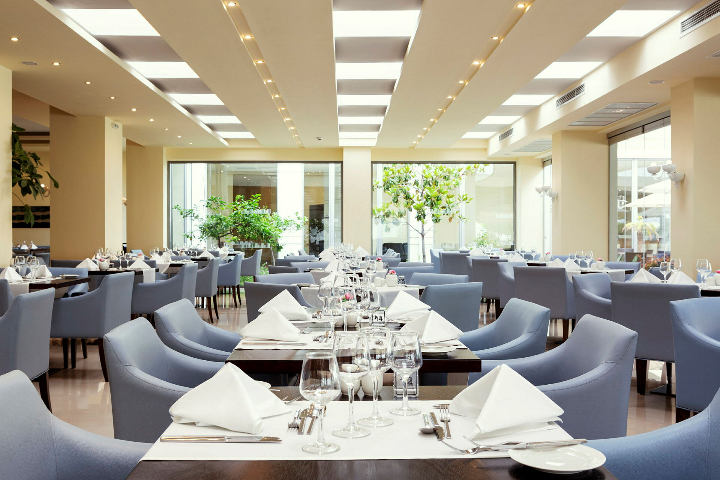 Bilde av en moderne restaurant med bord dekket og blå stoler. (AI-generert tekst)