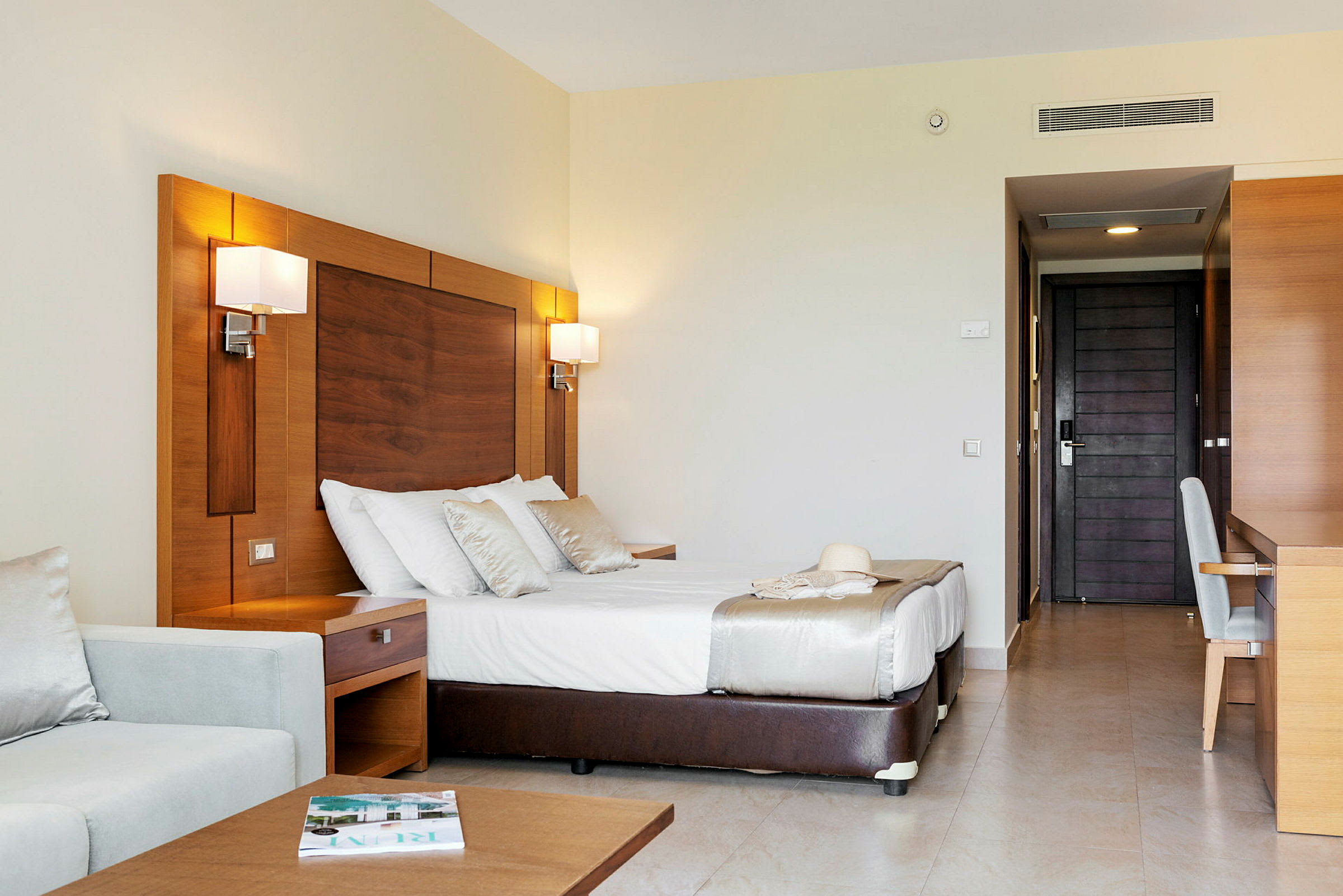 Et hotellrom med en dobbeltseng, en sofa og et skrivebord. (AI-generert tekst)