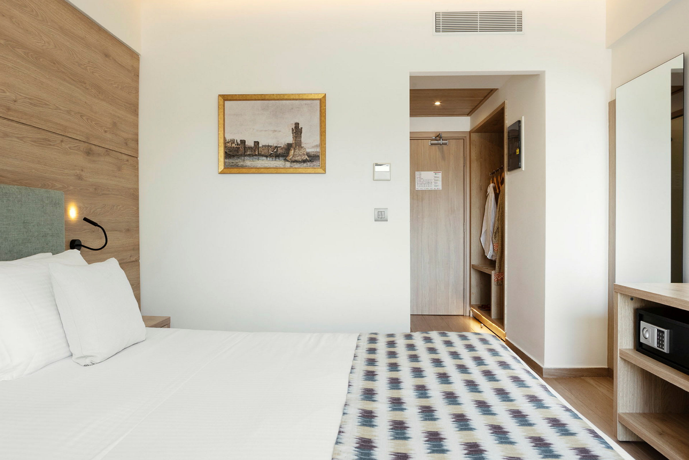 Et hotellrom med seng, veggmaleri og en åpen garderobe. (AI-generert tekst)