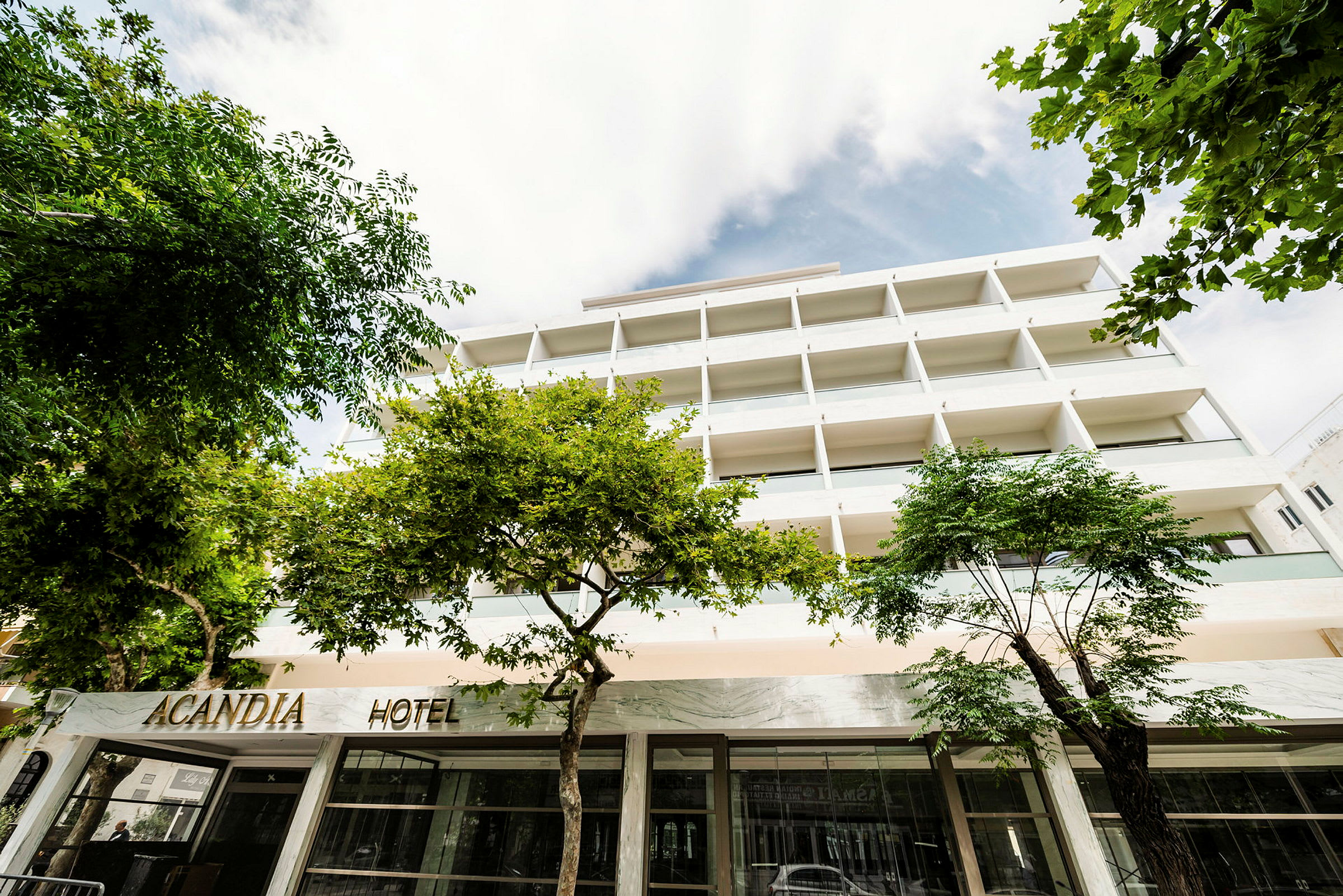 Bilde av hotellet Acandia med fasaden og omkringliggende trær. (AI-generert tekst)