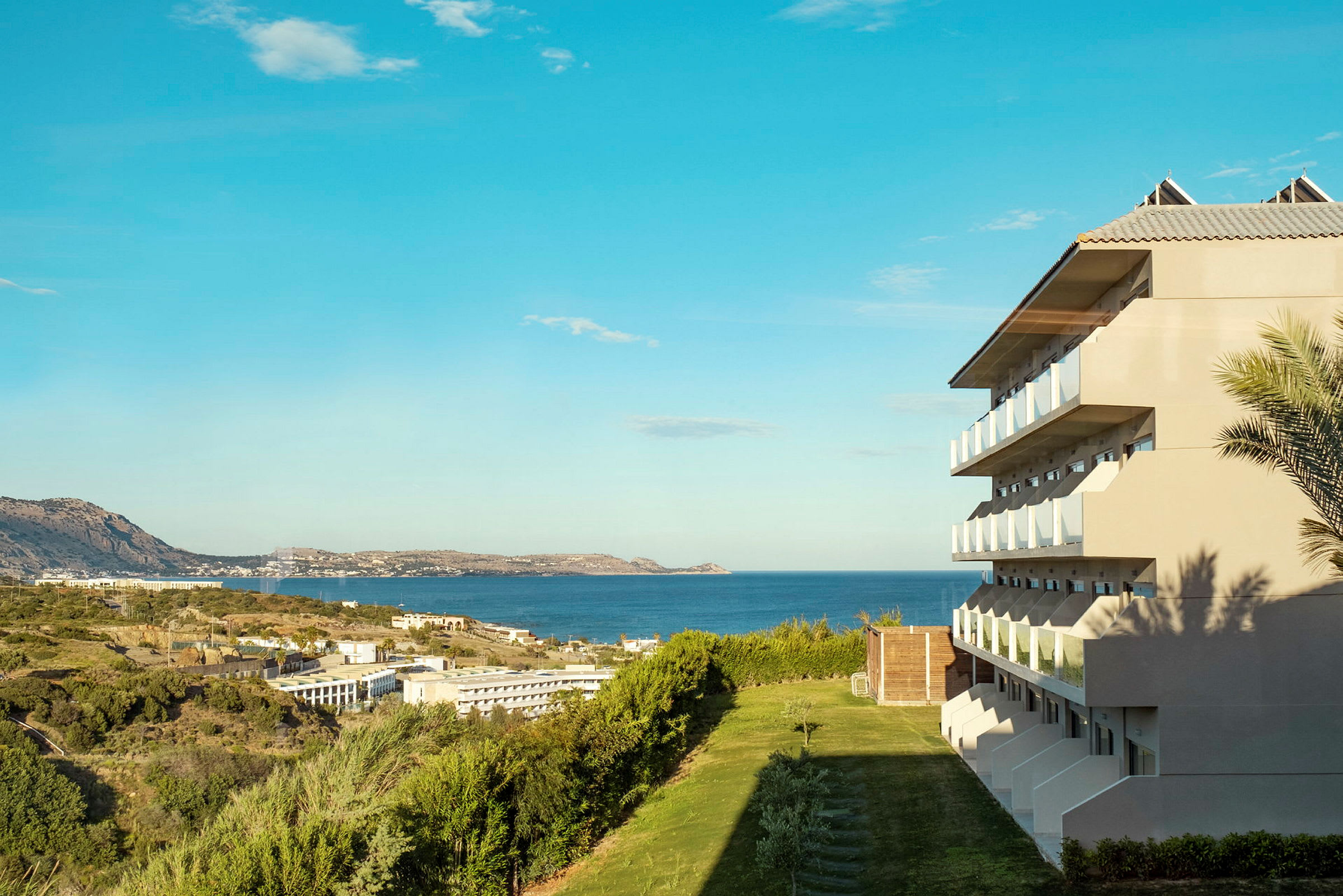 Bilde av et hotell med balkonger med utsikt over havet og grøntområder. (AI-generert tekst)