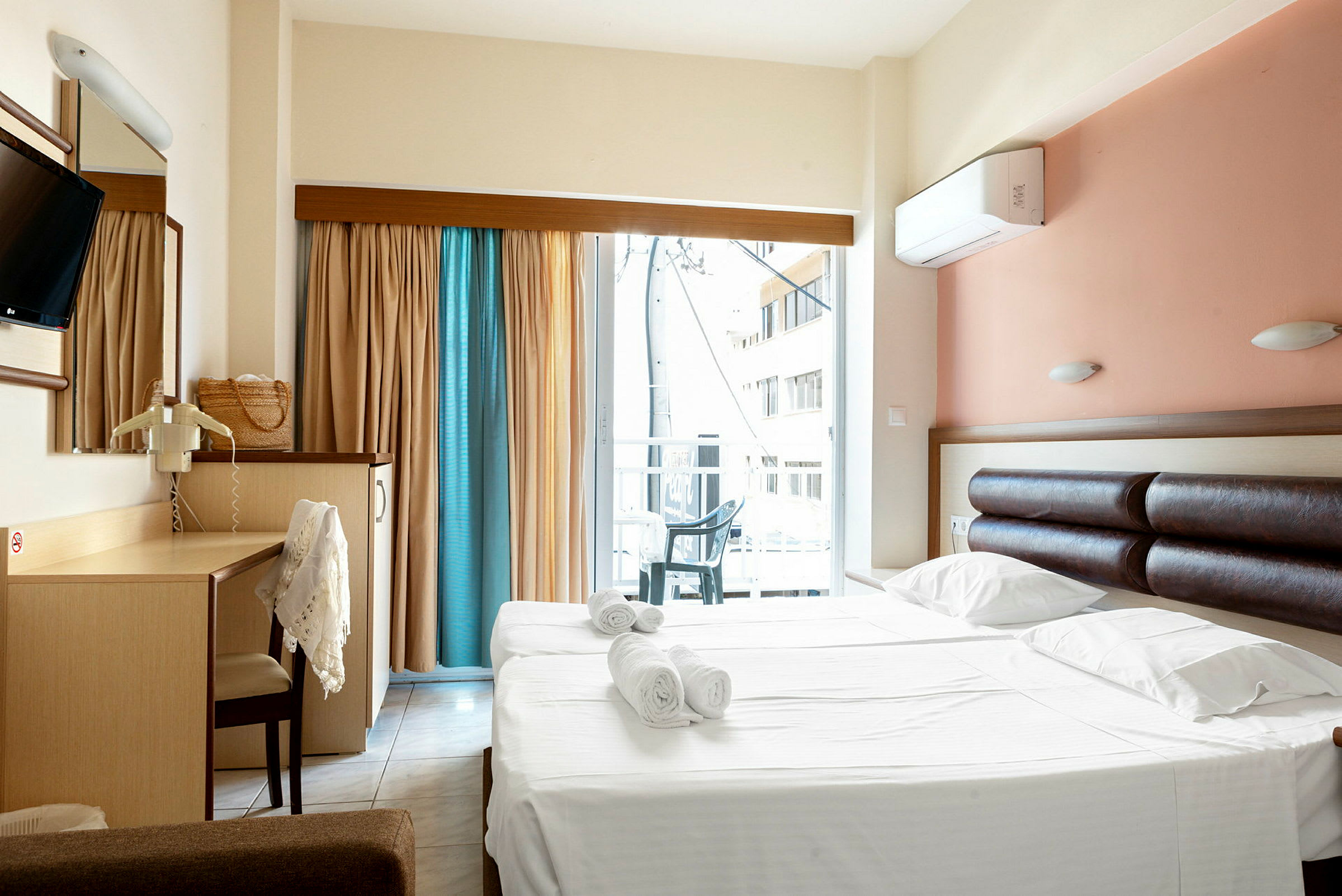Hotellrom med dobbeltseng og skrivebord, samt balkong med utsikt. (AI-generert tekst)