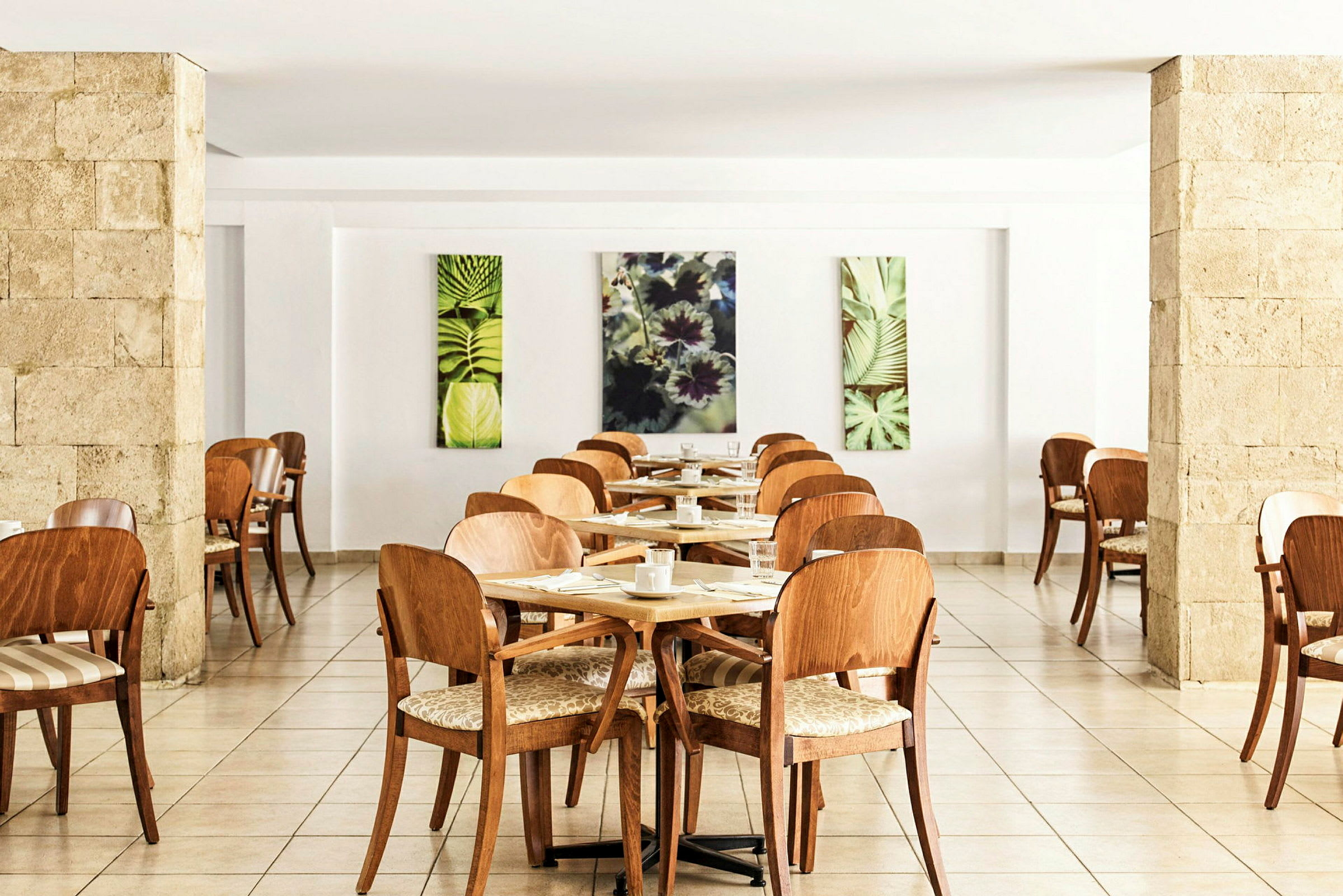 Restaurant med trestoler og bord, dekorert med kunstverk av plantemotiver. (AI-generert tekst)
