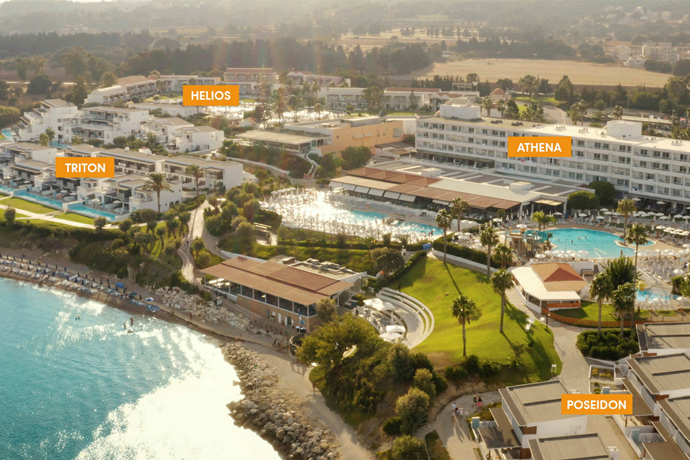 Luftfoto av resort med flere hotellbygninger og et basseng nær en strand. (AI-generert tekst)