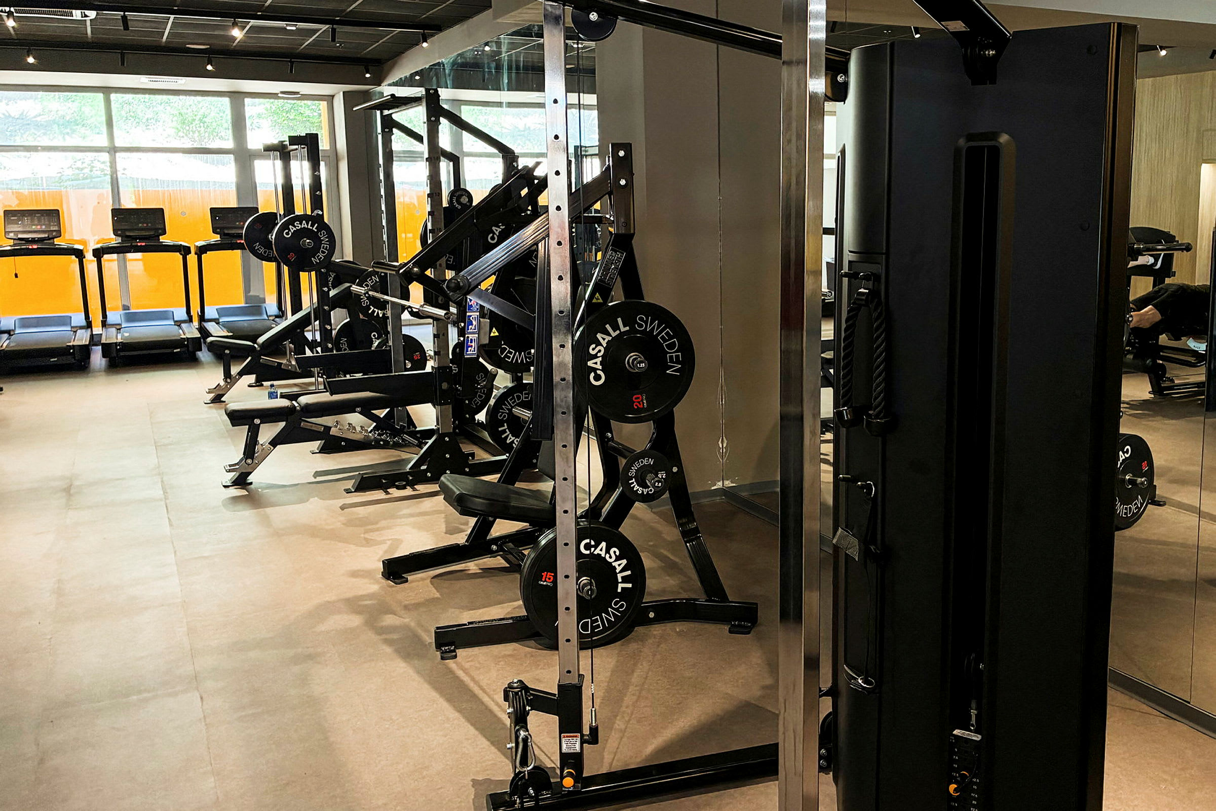 Et treningsstudio med treningsmaskiner, tredemøller og annen fitnessutstyr. (AI-generert tekst)