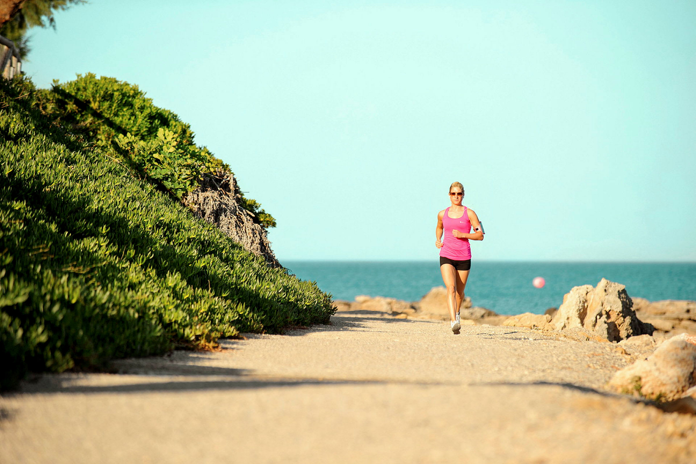 Person som jogger langs en steinete vei ved havet. (AI-generert tekst)