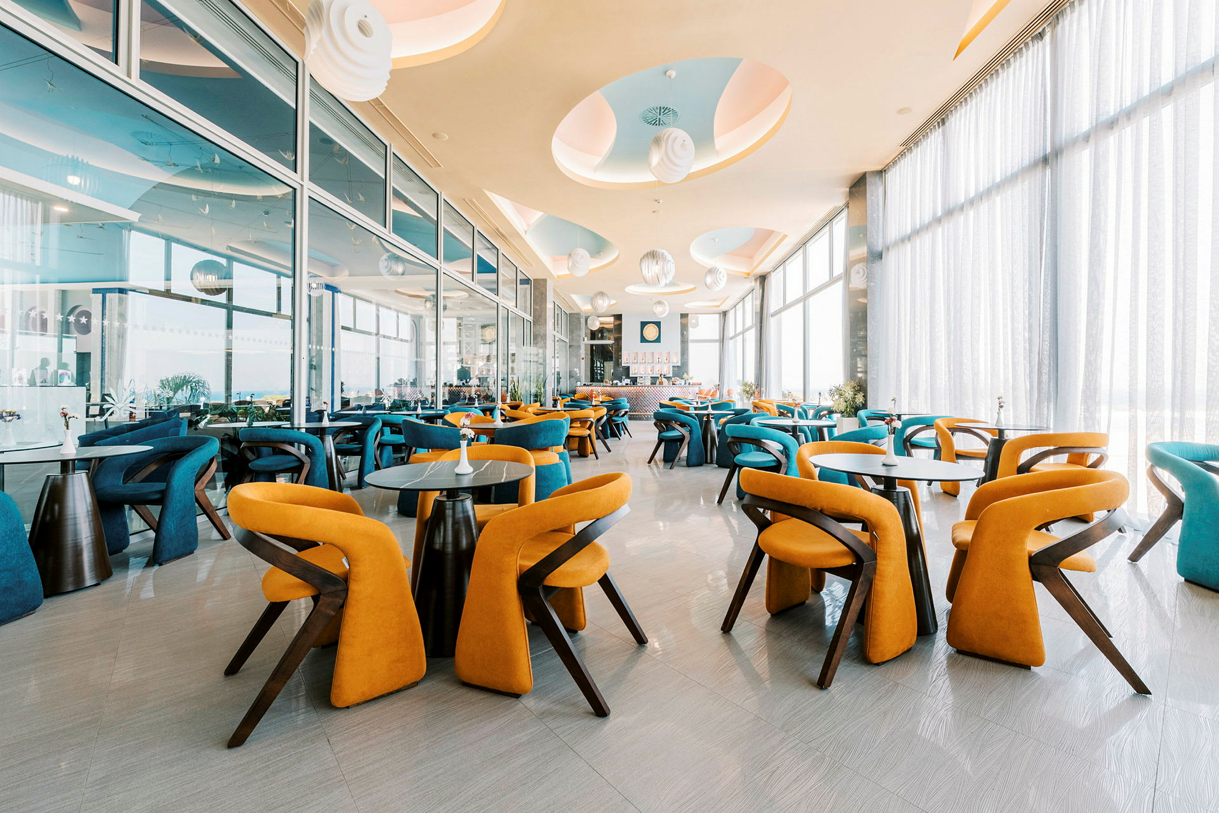 En moderne restaurant med fargerike stoler og store vinduer. (AI-generert tekst)