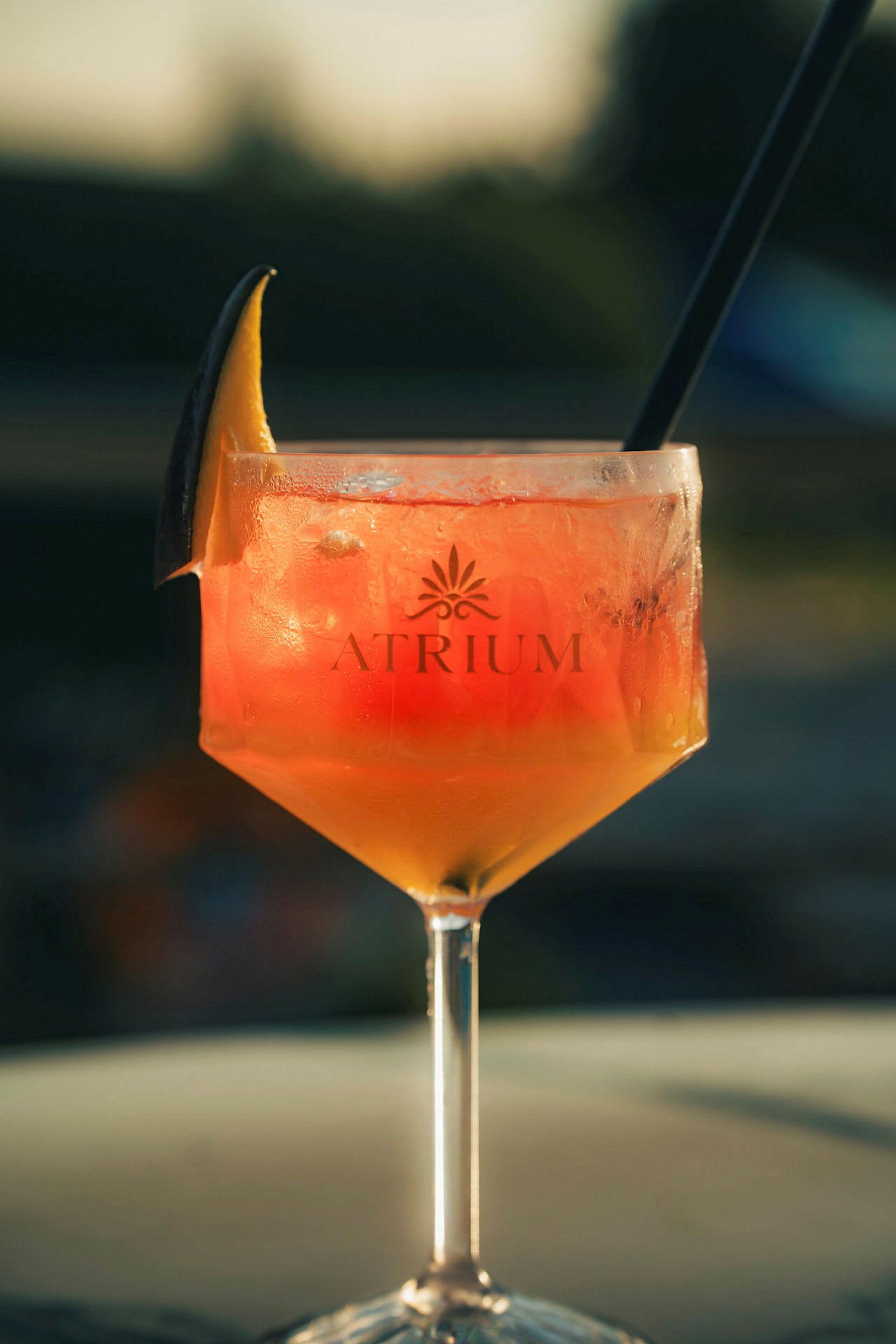 Et glass med en oransjefarget drink og isbiter, dekorert med en skive sitrusfrukt på kanten. (AI-generert tekst)