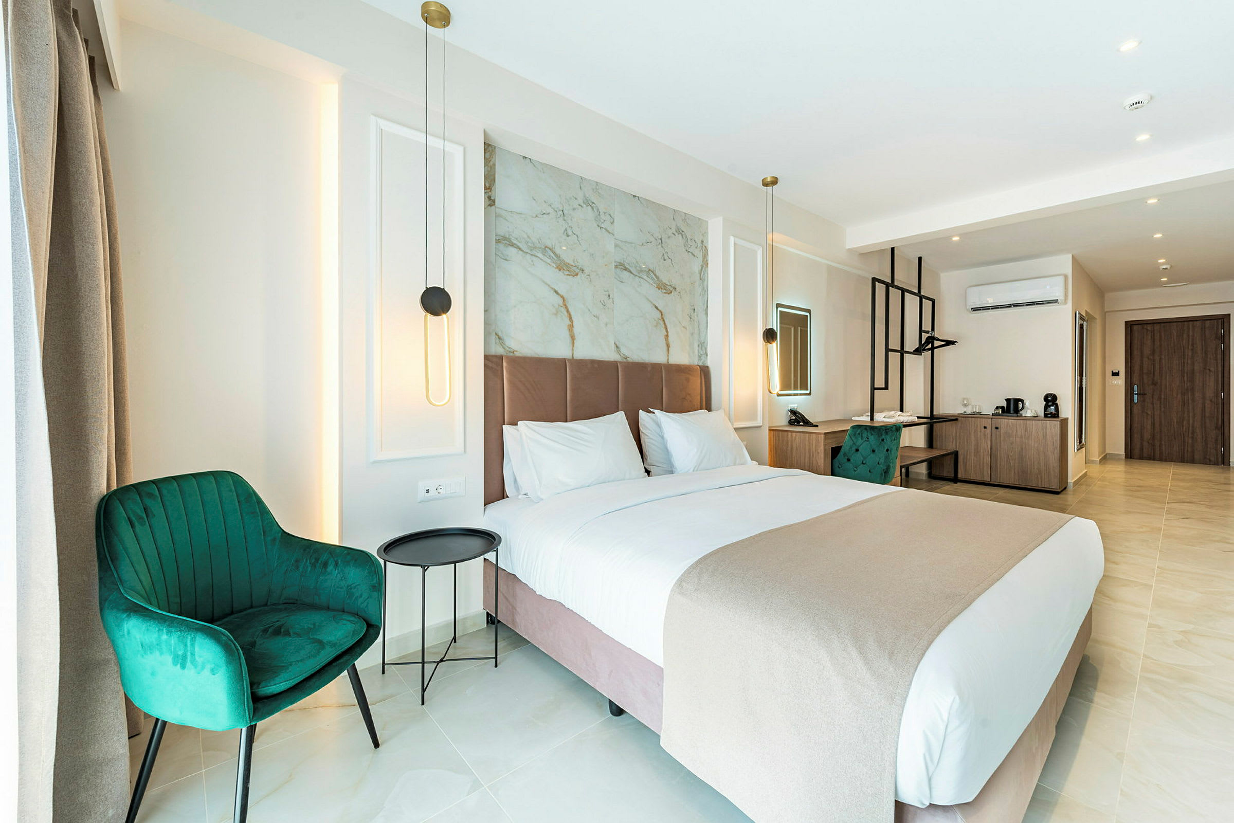 Et moderne hotellrom med en stor seng, grønne stoler og et skrivebord. Rommet er godt opplyst med vegglamper og har en stilren innredning. (AI-generert tekst)