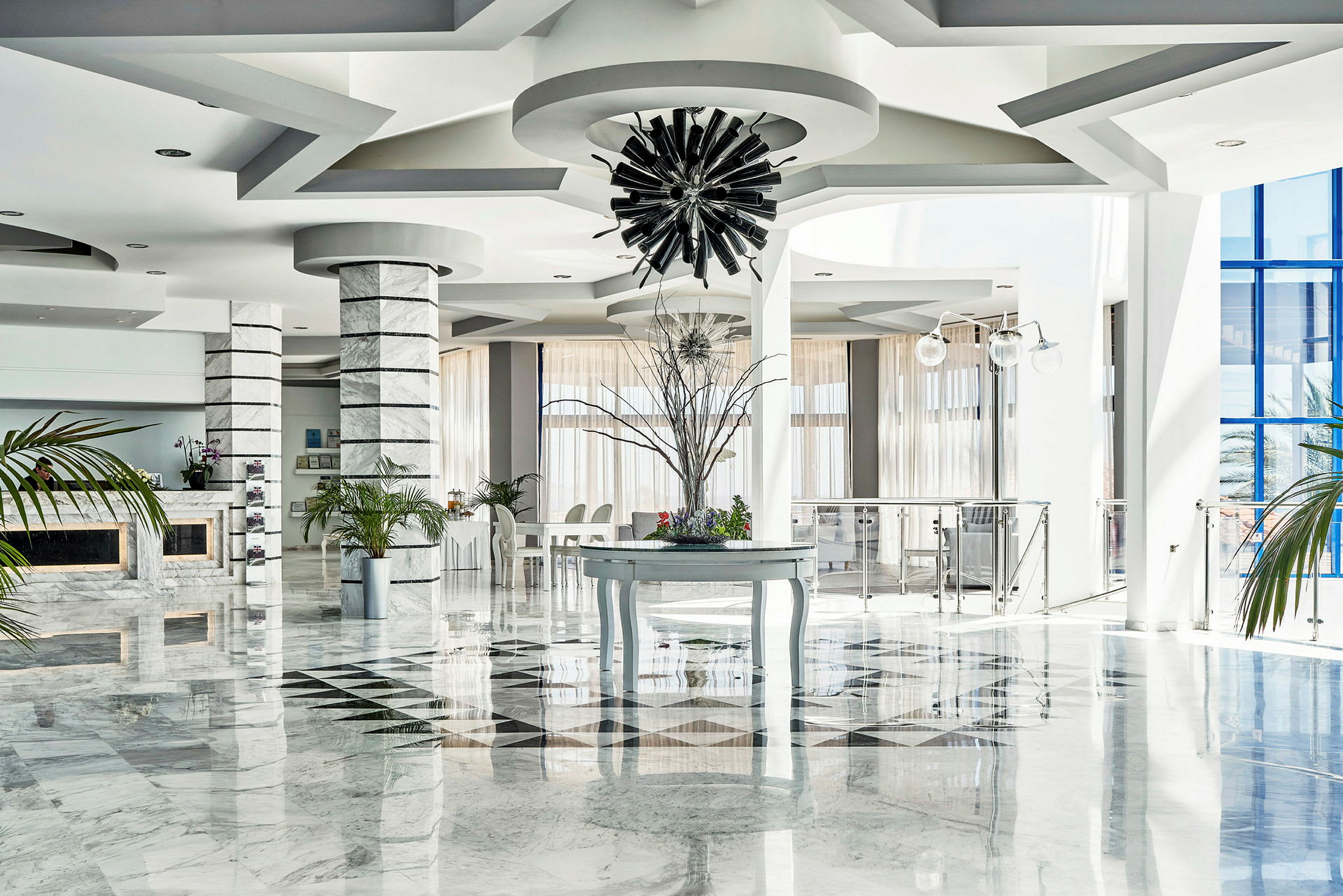 Interiør av en lys hotellobby med marmorgulv, dekorative søyler og moderne innredning. (AI-generert tekst)
