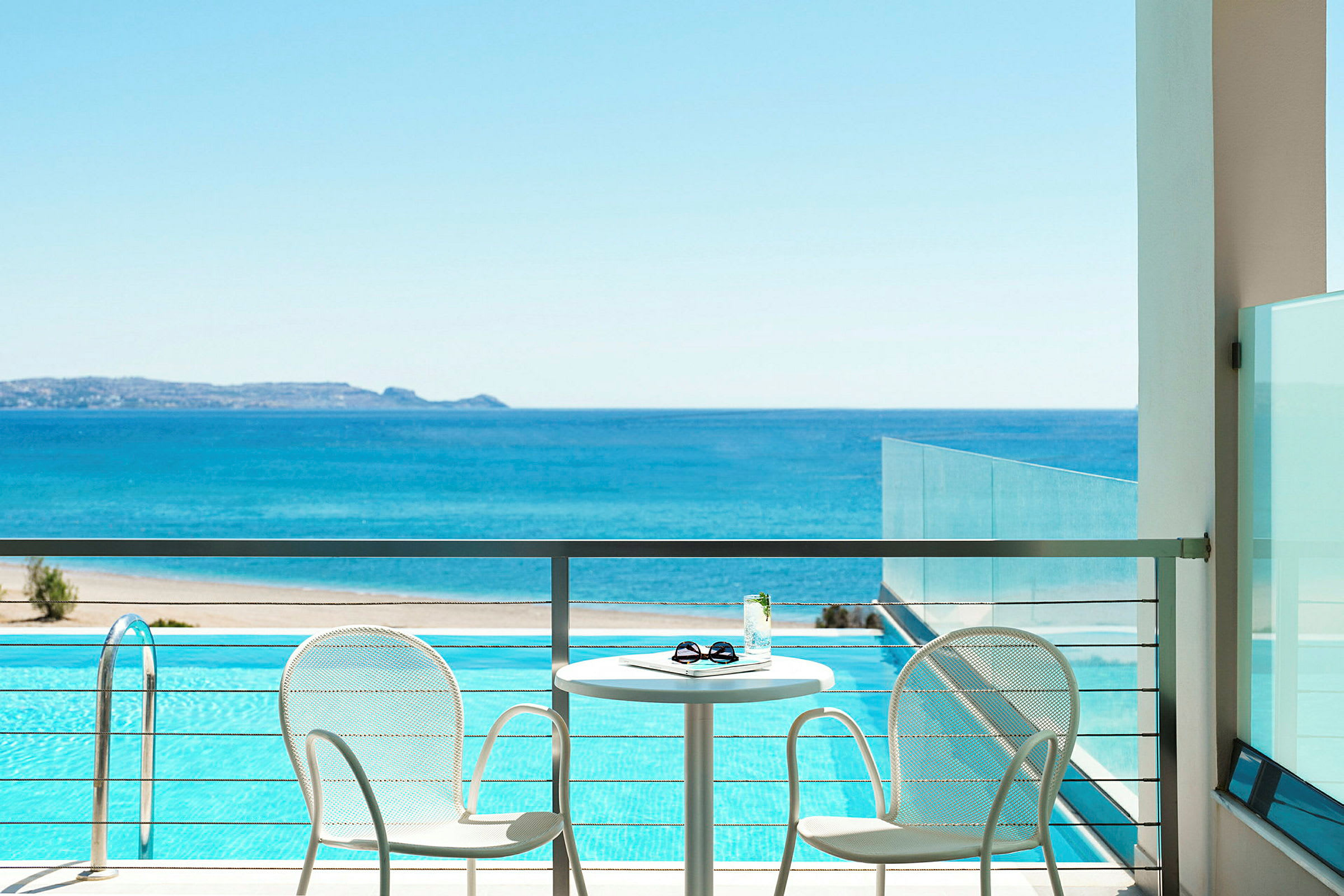 Terrasse med to stoler og et bord med utsikt over havet og et basseng. (AI-generert tekst)