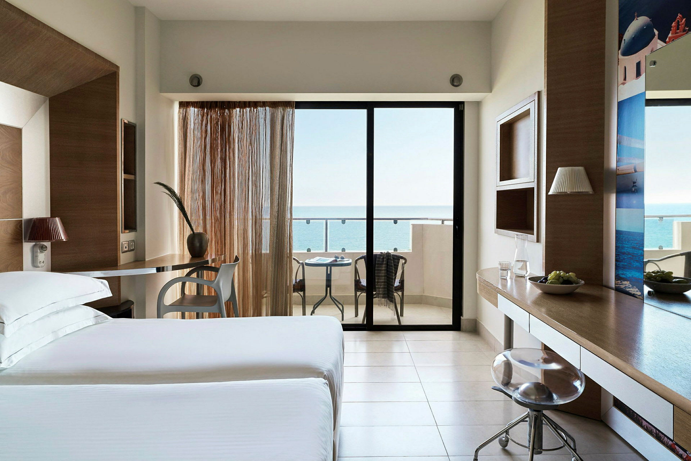 Hotellrom med moderne innredning, sittegruppe og balkong med havutsikt. (AI-generert tekst)