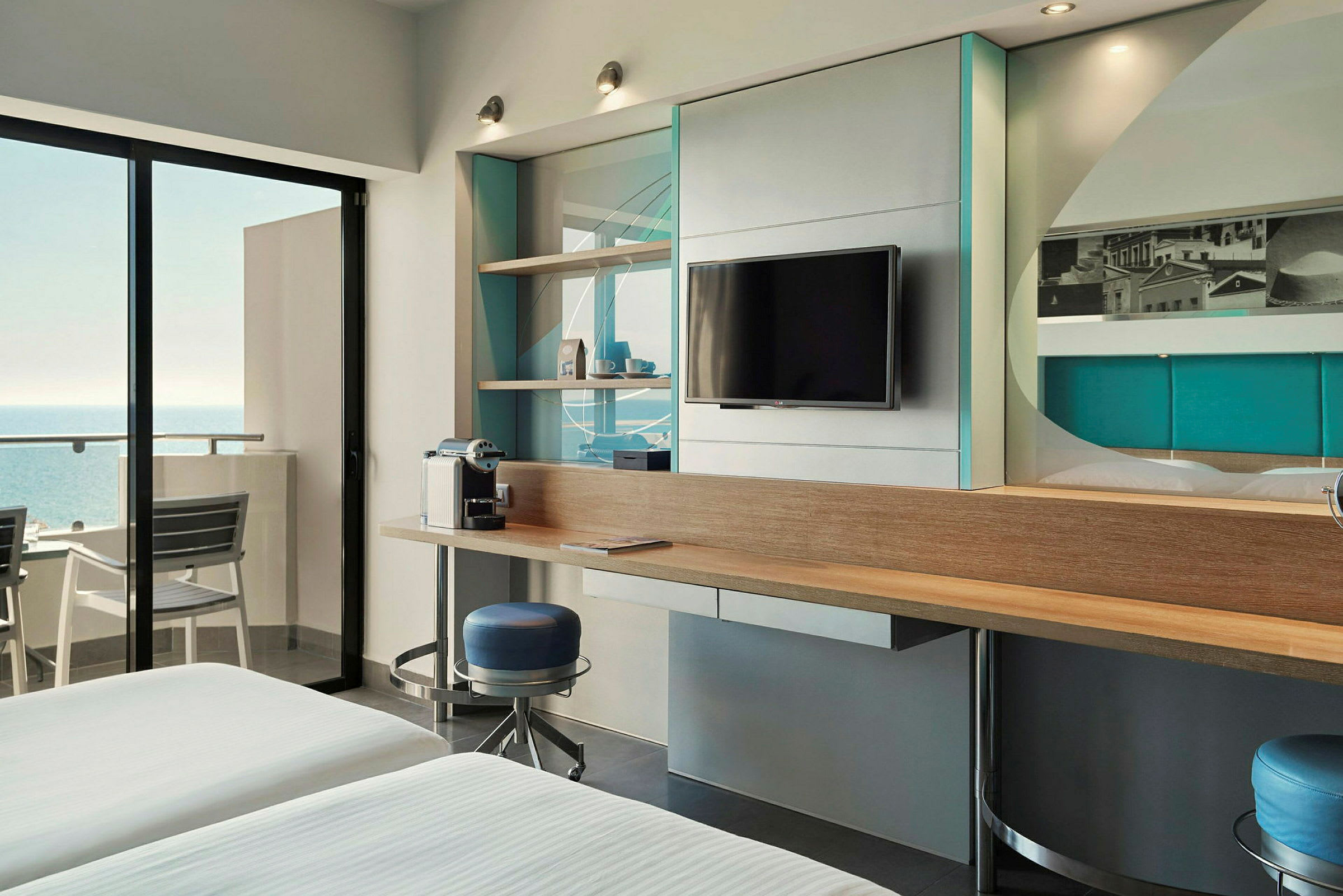 Et moderne hotellrom med havutsikt, en TV på veggen og en kaffetrakter på et skrivebord. (AI-generert tekst)