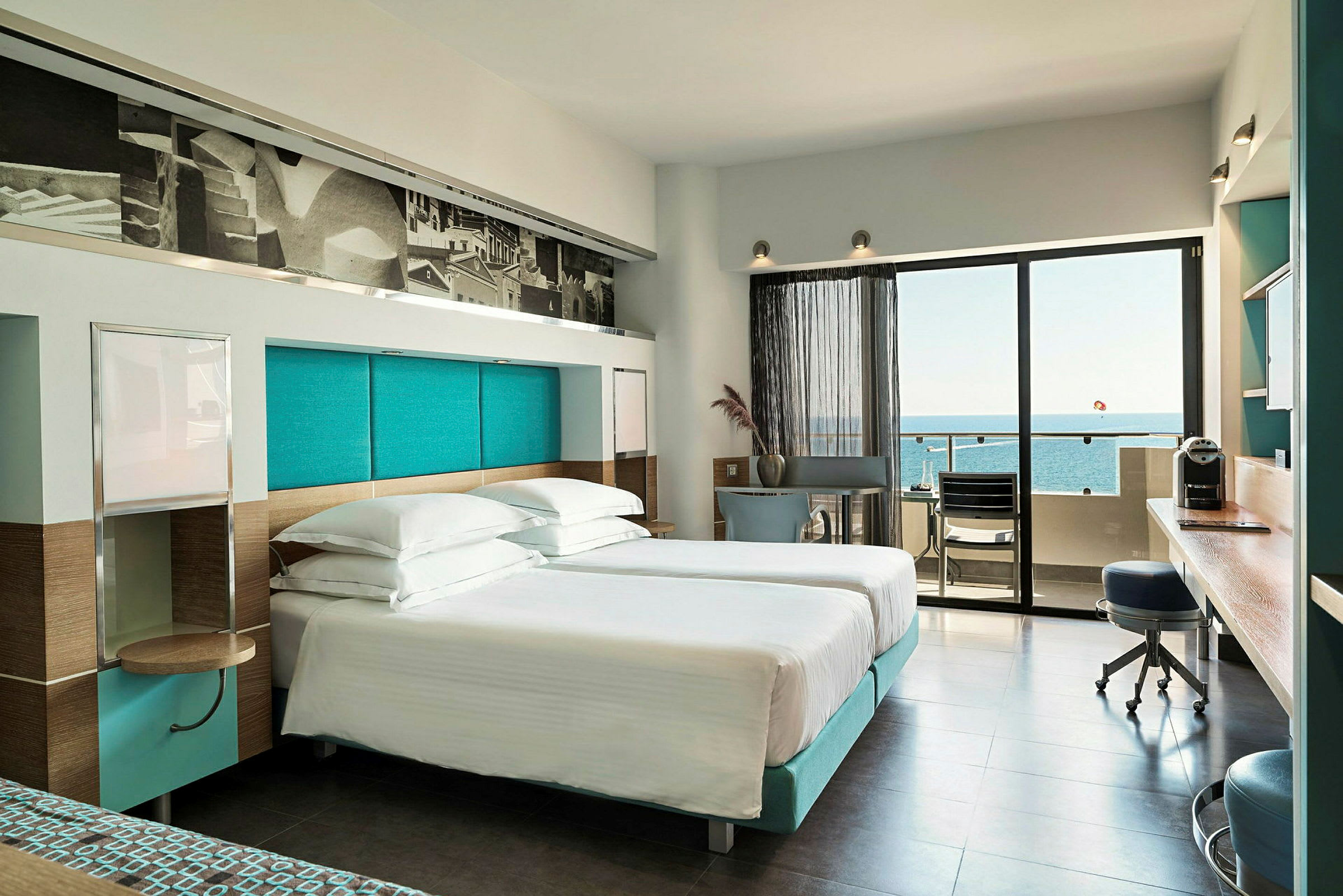 Moderne hotellrom med dobbeltsenger og utsikt over havet fra balkongen. (AI-generert tekst)